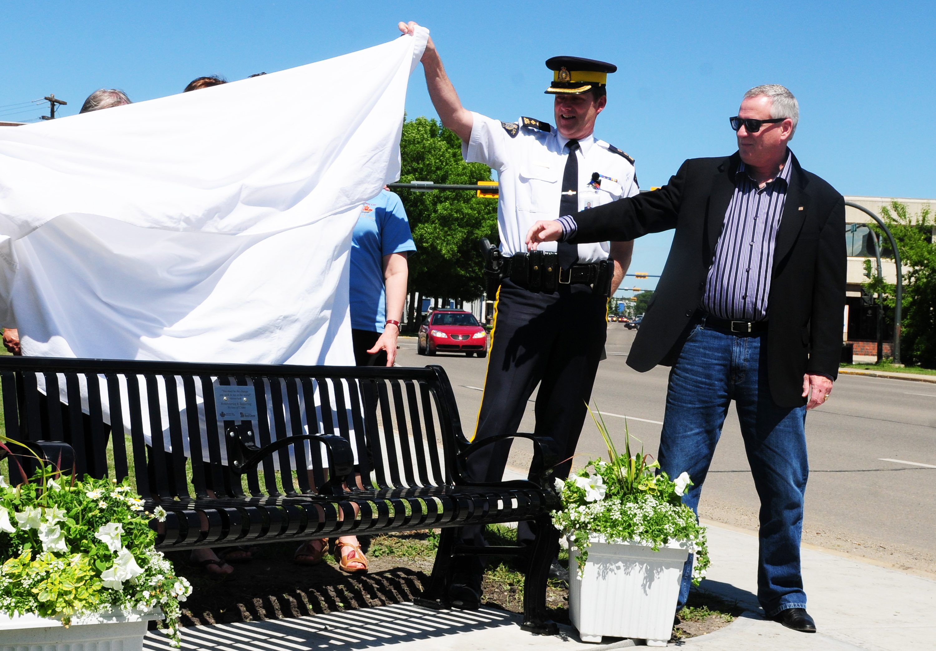 IMPORTANT SPOT- RCMP Supt. Brian Simpson and City Councillor Buck Buchanan unveil a new bench in front of the new RCMP detachment recently