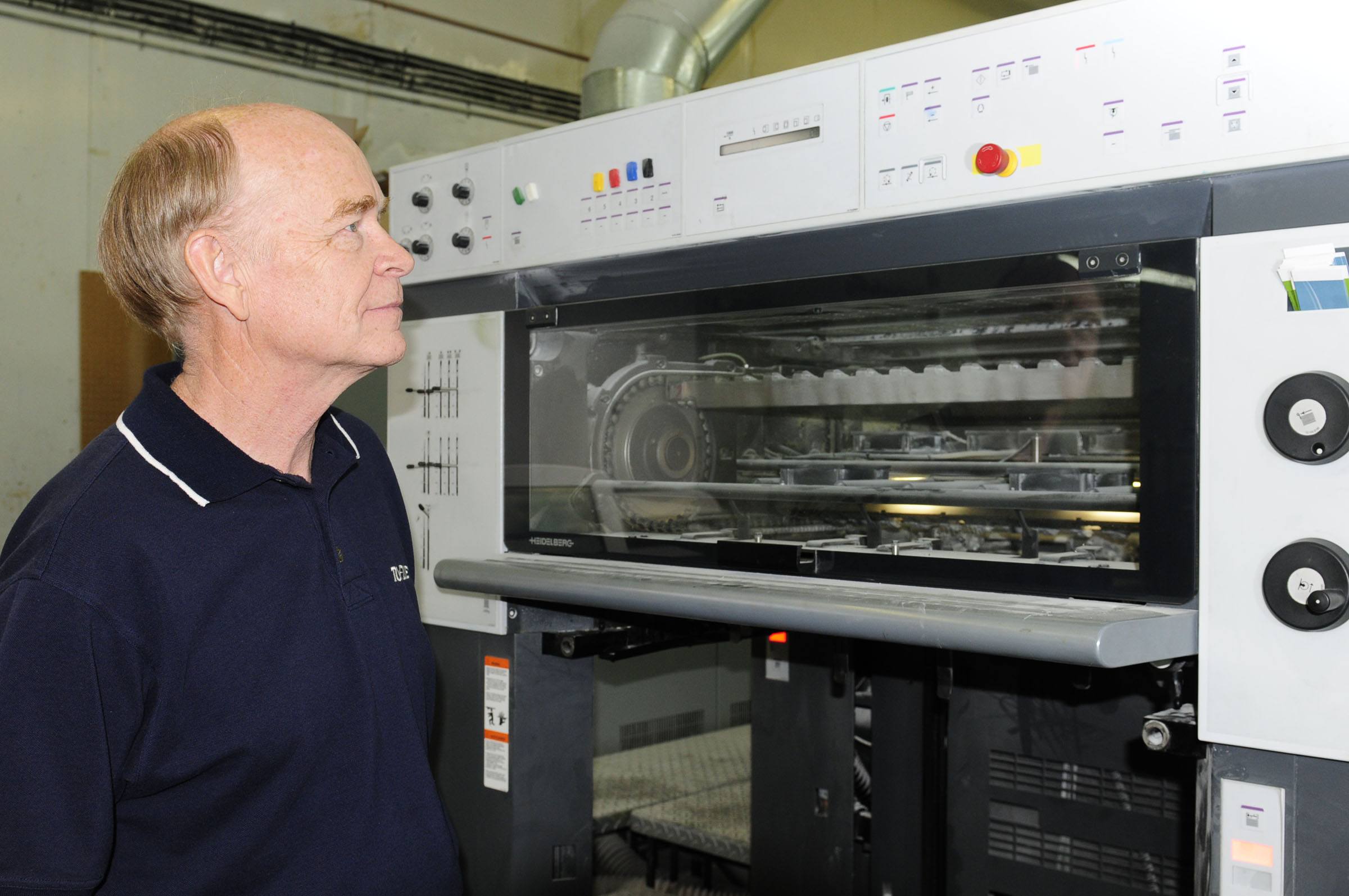 Dave Rideout stands beside a $1.7 million printing press at Prolific Graphics where he is currently working due to the shutdown of his family run company Adviser Graphics