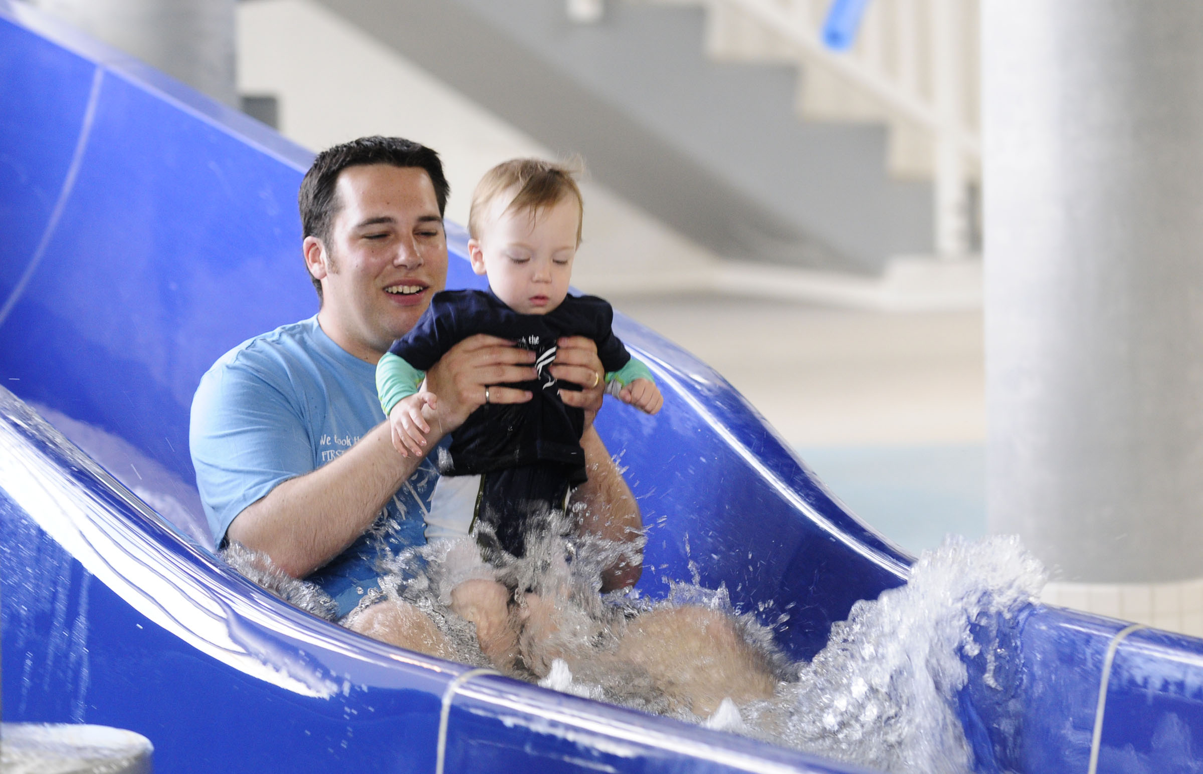 Two lucky families won a chance to be first down the new slides during the grand re-opening of the G.H. Dawe Community Centre Tuesday. Kyle Reed holds his son Elijah