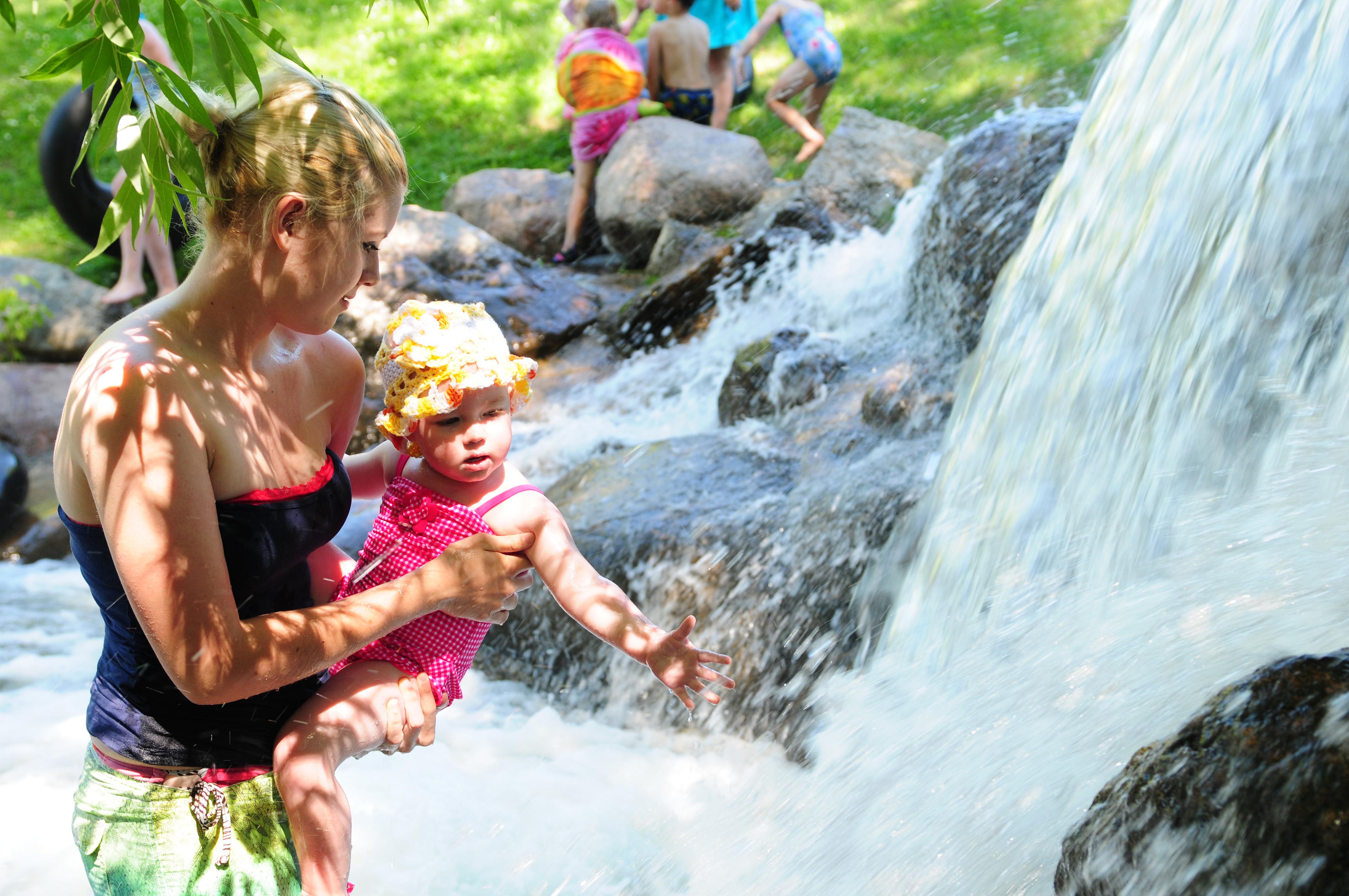 COOLING DOWN- Candice Morse holds Sophie Pearce up to the waterfall at Discovery Canyon to feel the cool water in the summer heat.