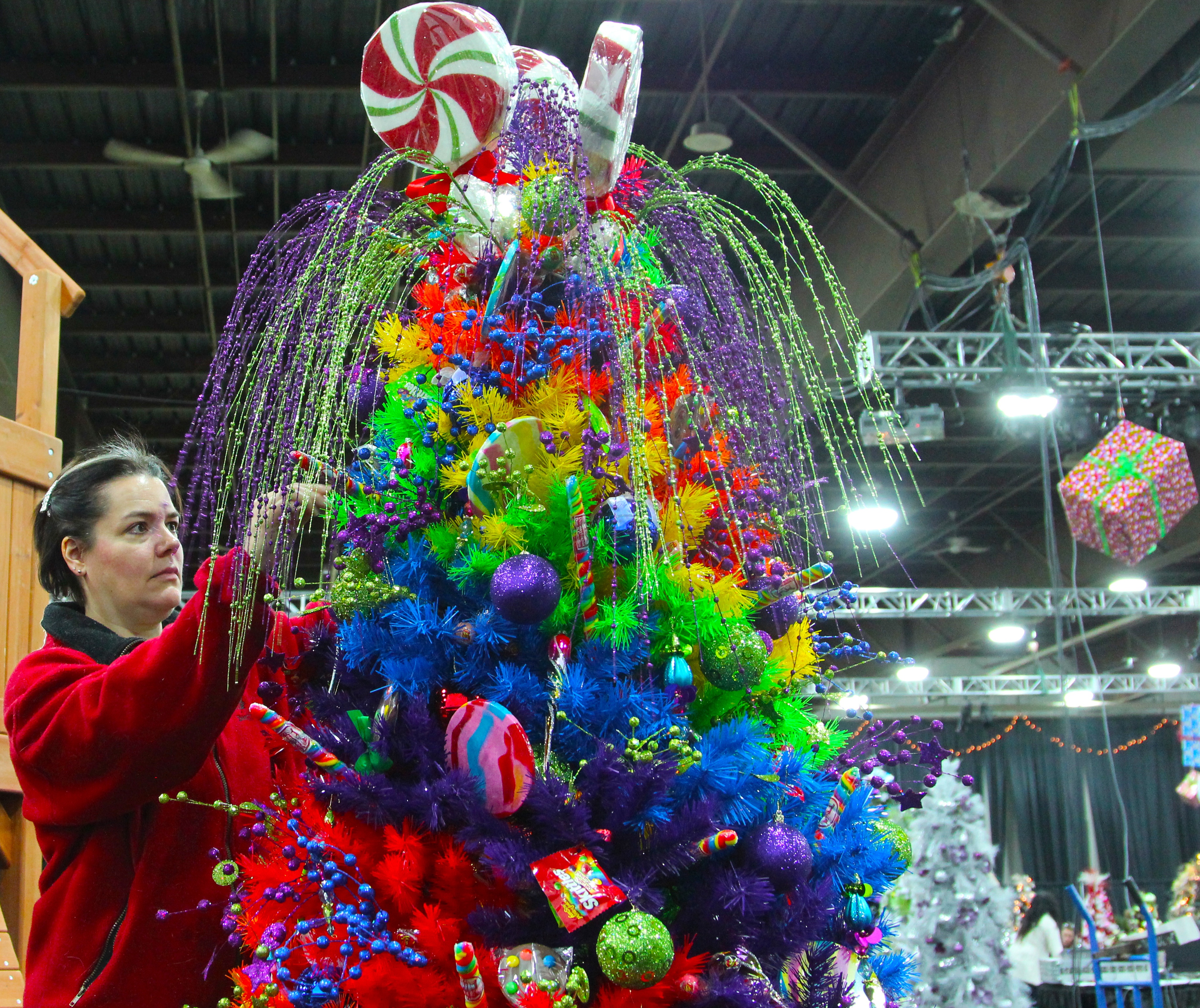 LOLLIPOPS & RAINBOWS – Martine Giguere puts the finishing touches on a bright candy-themed Christmas tree that will be on display at this year’s Festival of Trees.