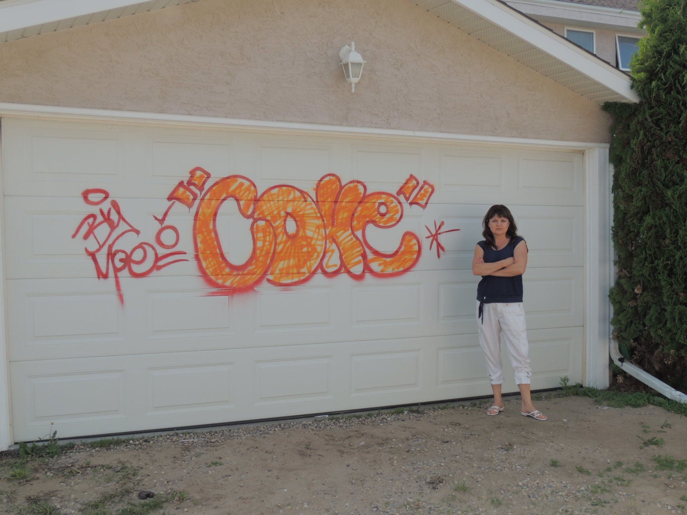 FIGHTING BACK - Marina Coldwell stands in front of her garage in Anders on the Lake. Her property as well as a number of her neighbours’ properties were spray painted last week.