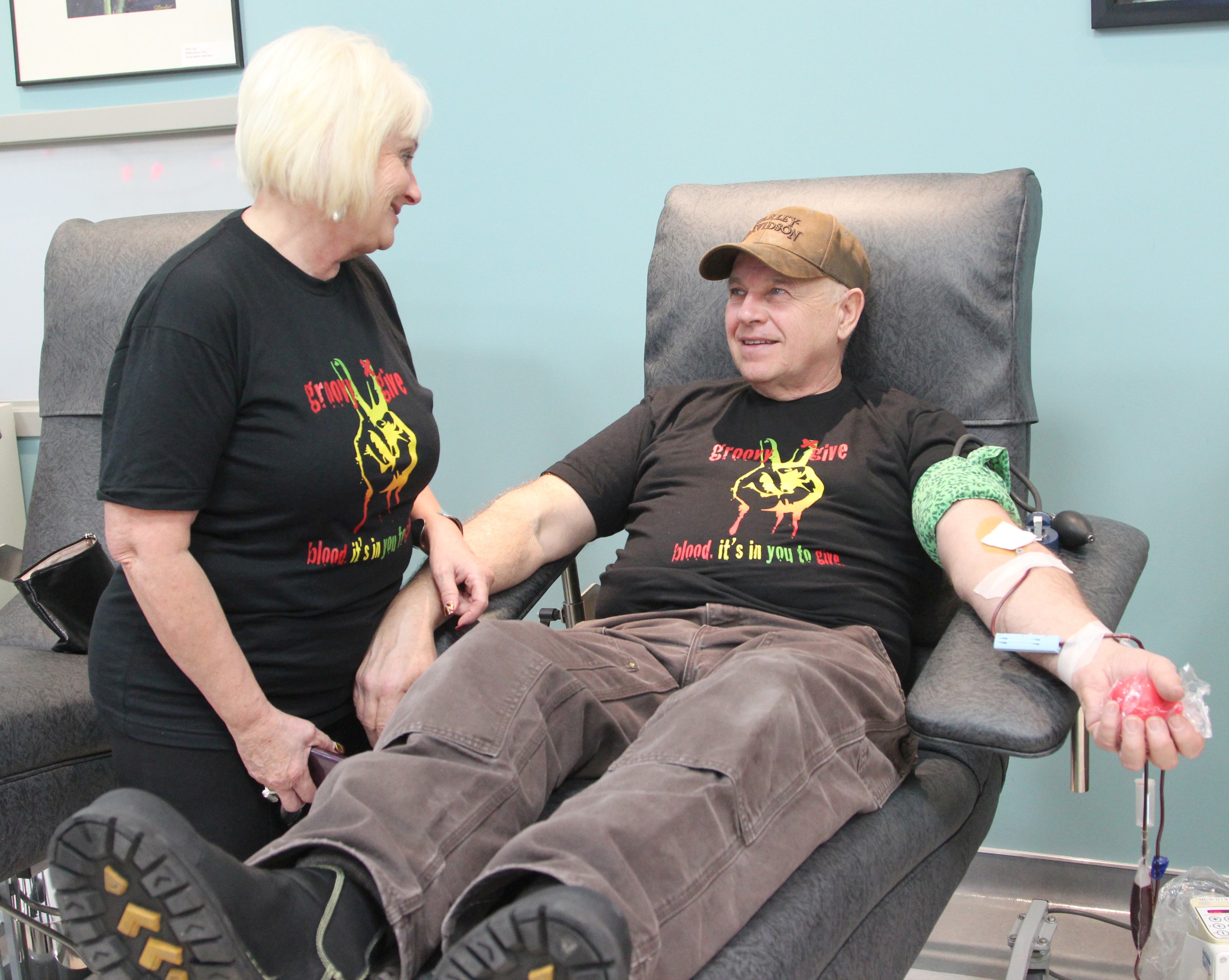 TRIBUTE – Jan Hurlburt stands by her husband Robin while he donates blood on Monday at the Canadian Blood Services Clinic. They were attending the launch of the Giving Holiday Miracles campaign in memory of their late son Joshua.