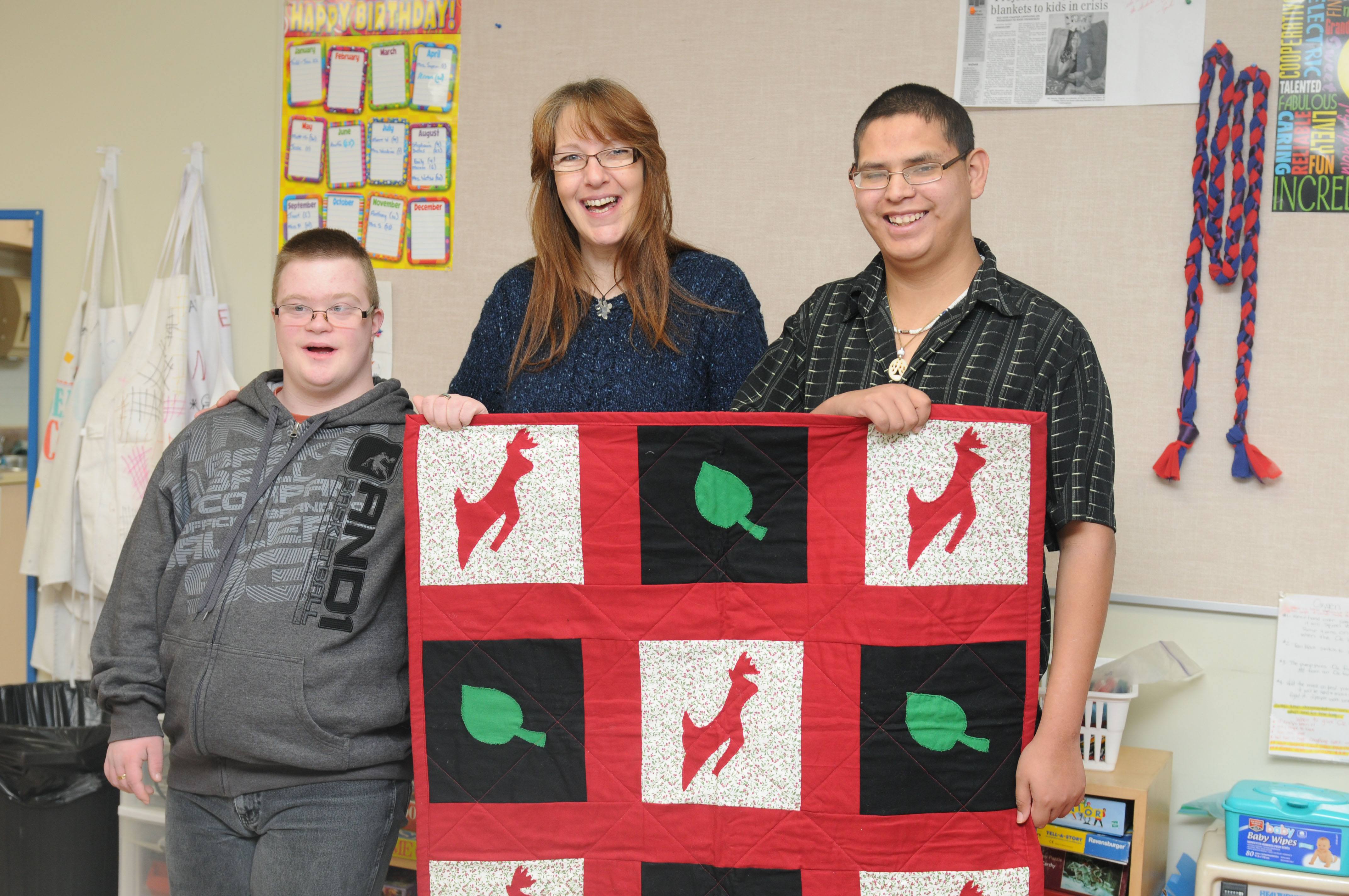 PROUD- Angie Garcia with the Red Deer Linus Project holds up the beautiful quilt with Pathways class members from left Matthew Mickey and Arron Lightening.