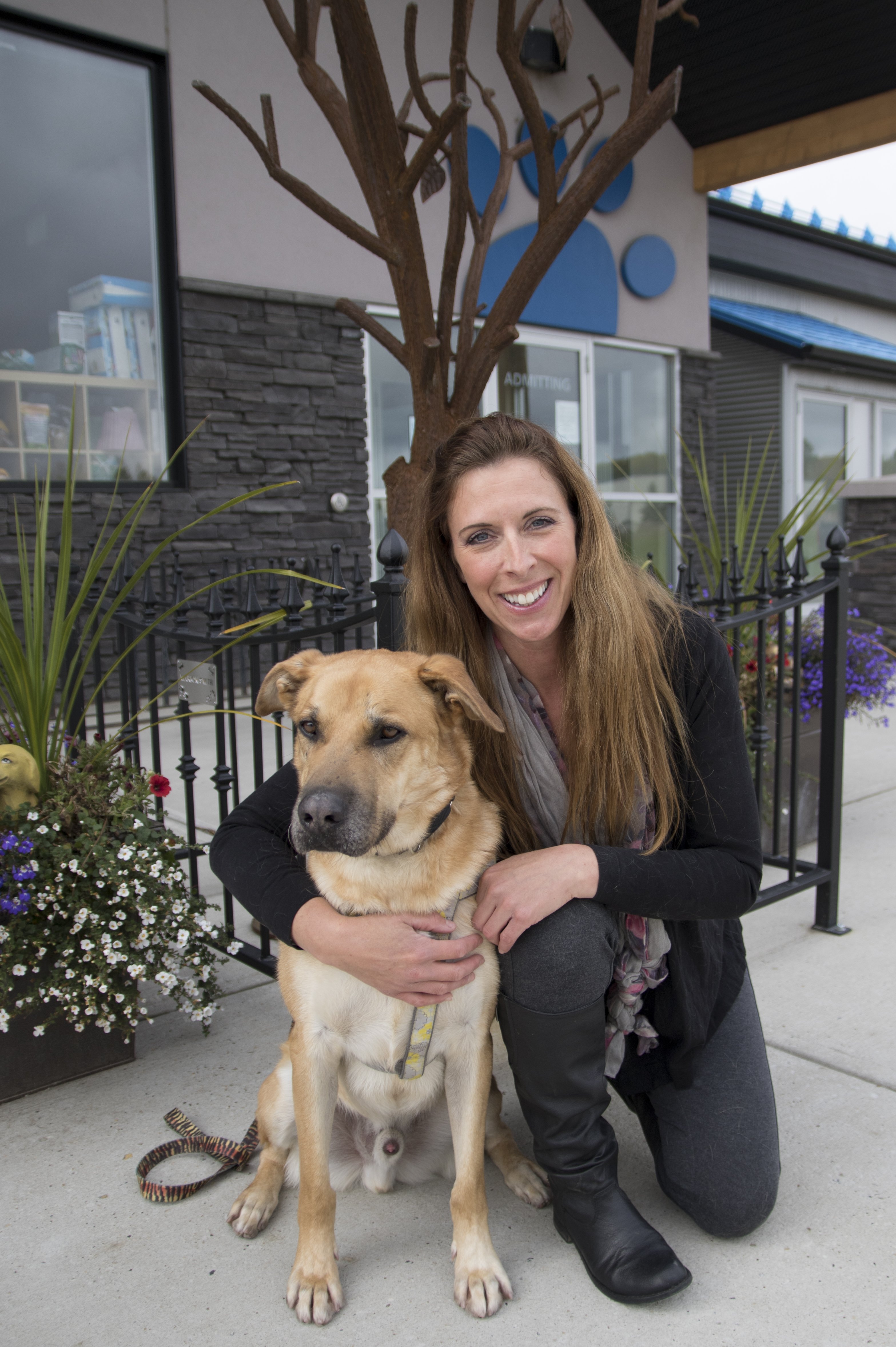 TAKING A REST – Red Deer and District SPCA Executive Director Tara Hellewell and rescue dog Tommy take a moment in front of the new memorial tree at the Red Deer SPCA