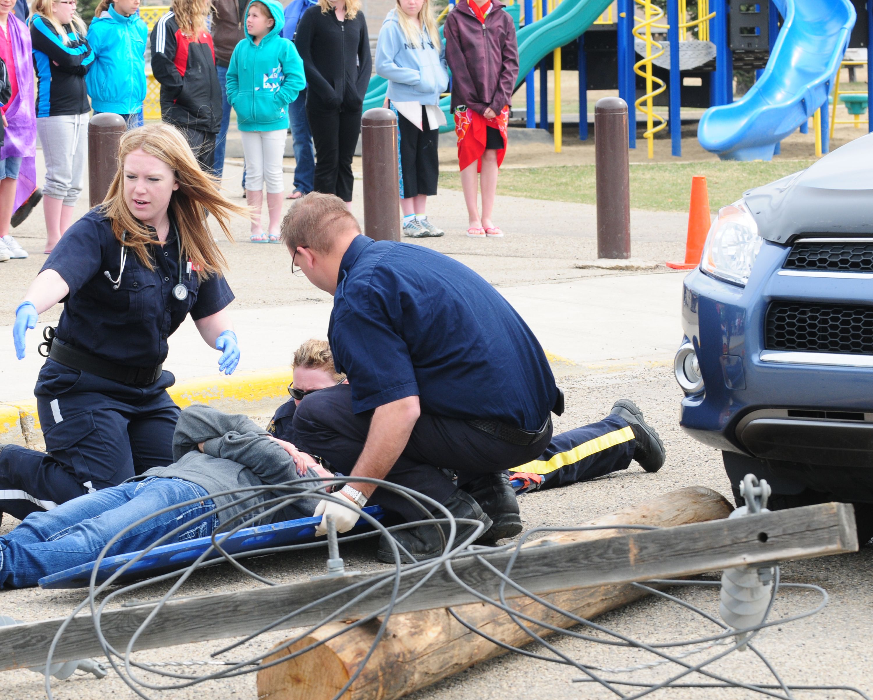 ACTING- Lacey Wutzke lays on a stretcher while a crew from the City’s emergency services looks after her during a reenactment of an accident at Holy Family School for Grade 5 students.