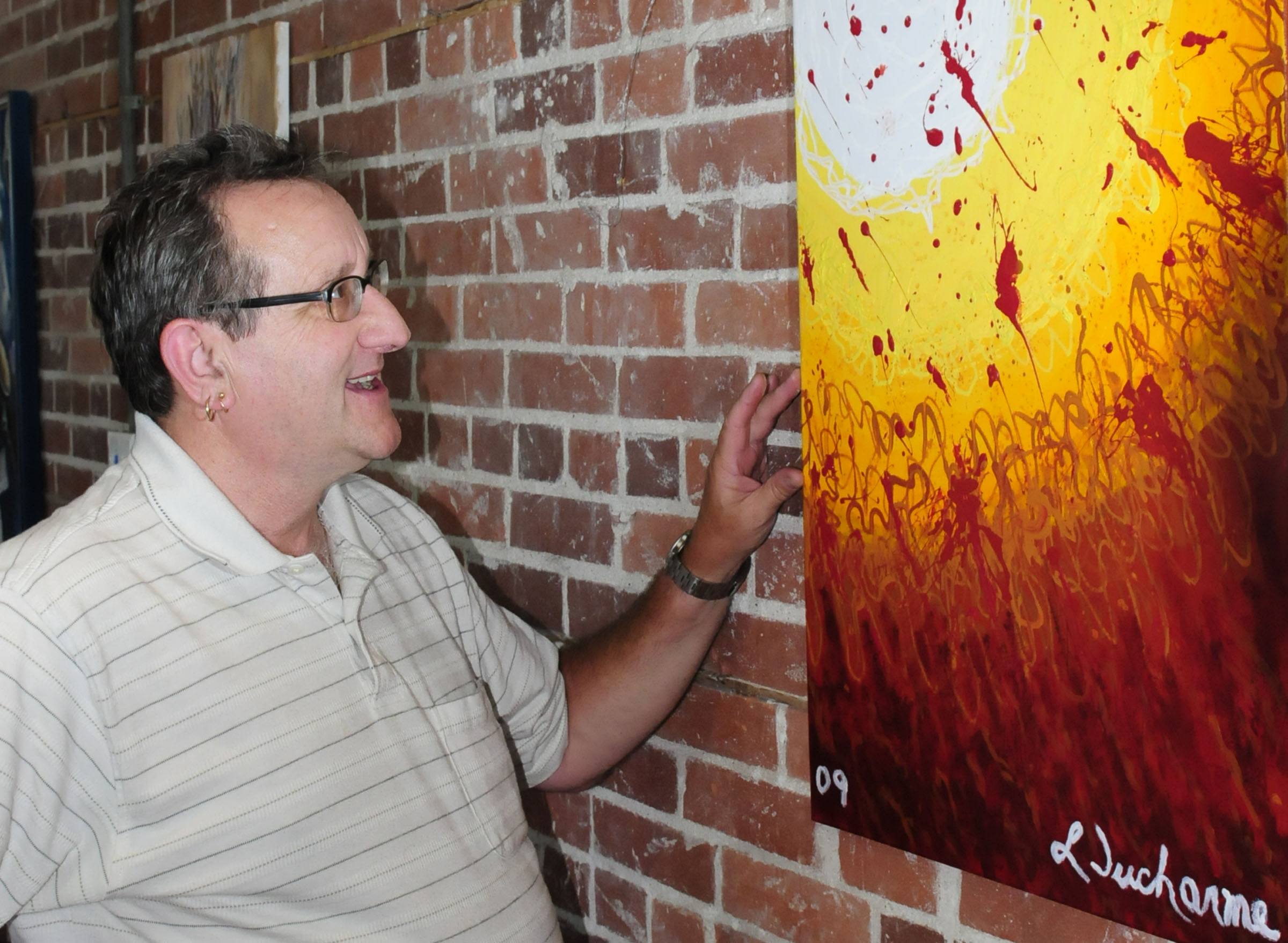 Red Deerian Leo Ducharme stands by one of his colourful creations depicting the sun. His work will be featured at The Loft on Gaetz during the month of August.