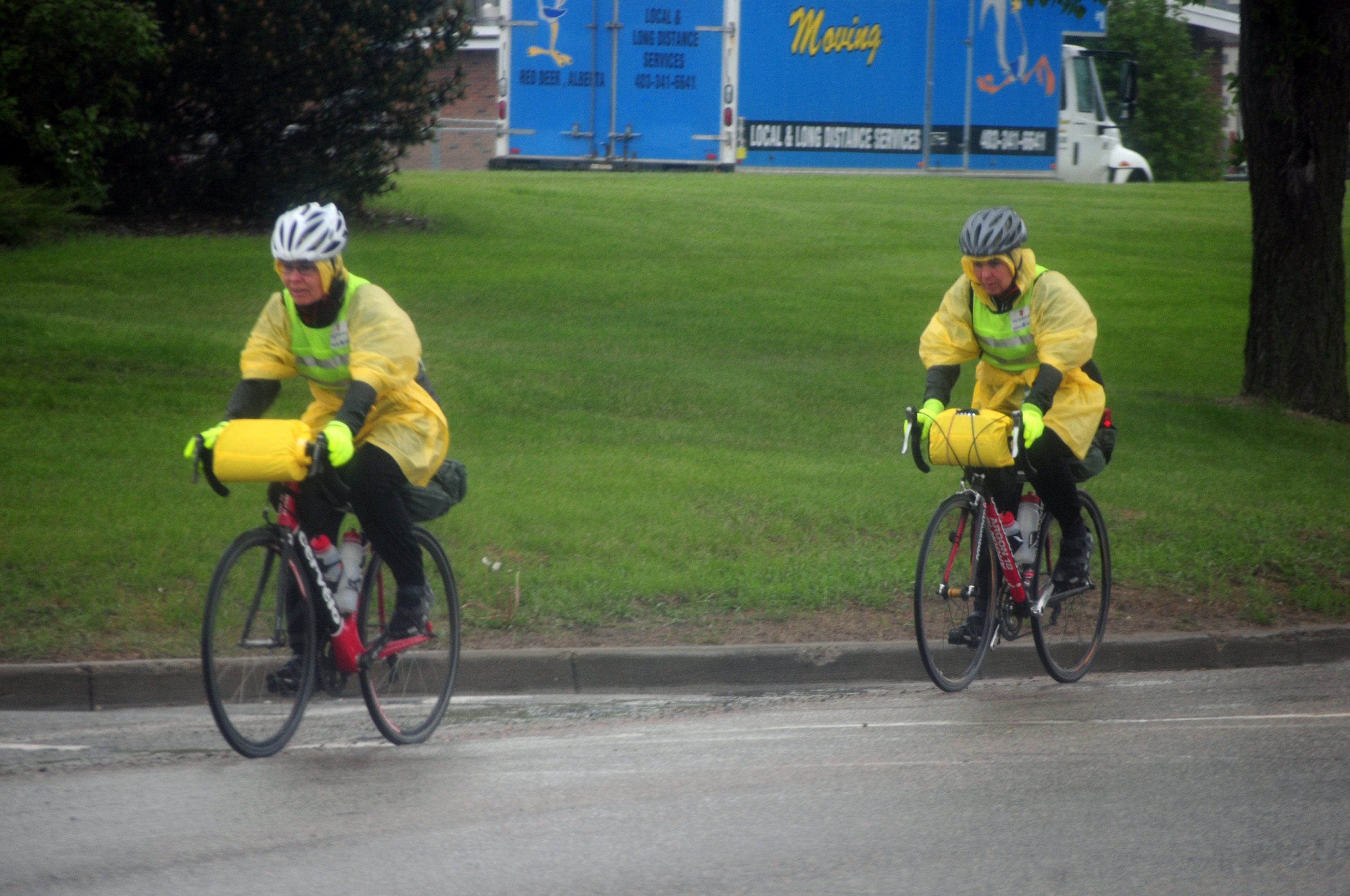 WET RIDE- Two pedal bikers braved the rain Saturday morning along 67 St. despite the continuous downpour.