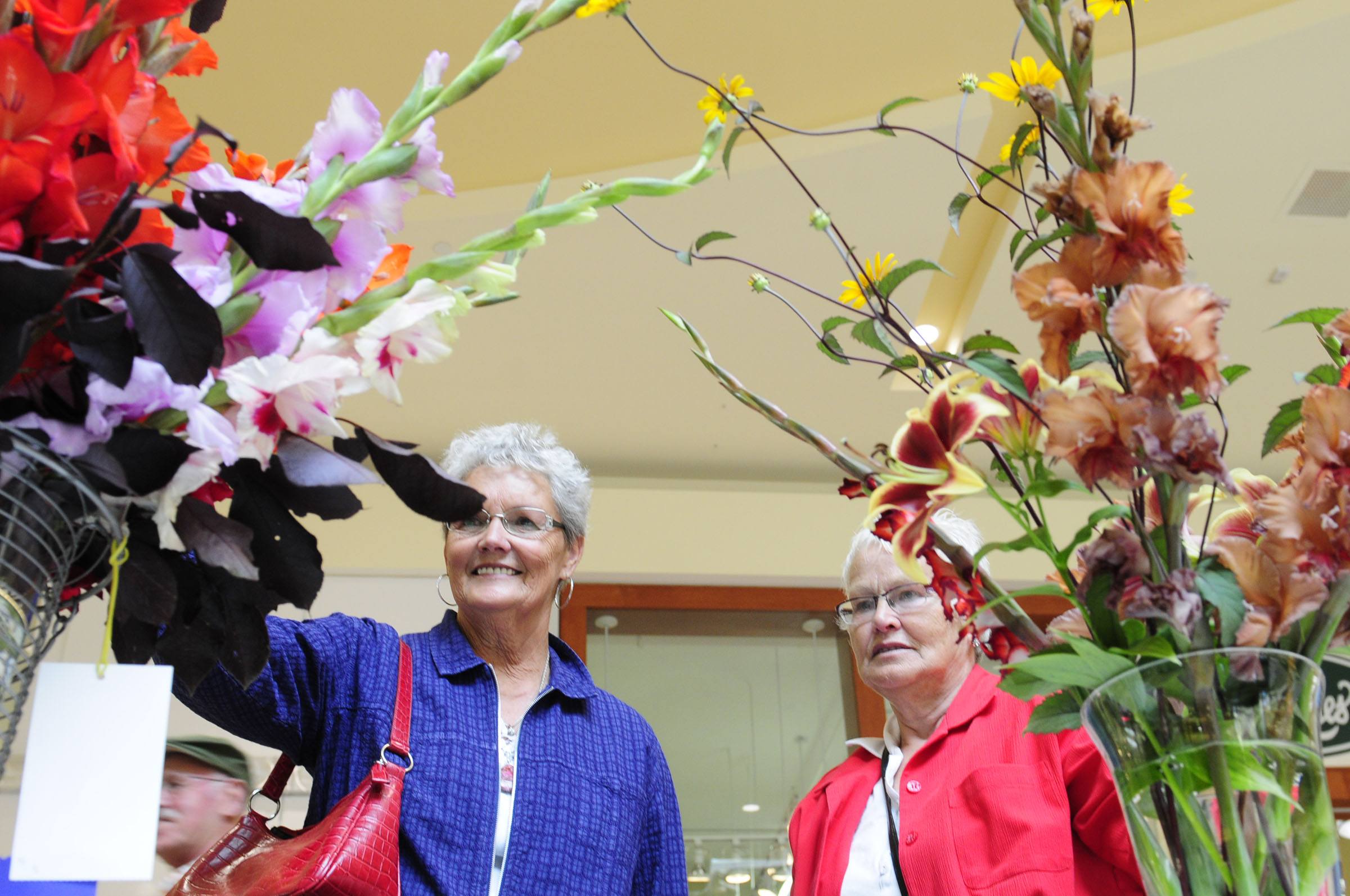 Nancy Gordon and Gail Pugh enjoy the colourful flower arrangements Saturday during the flower show at the Bower Mall in Red Deer.
