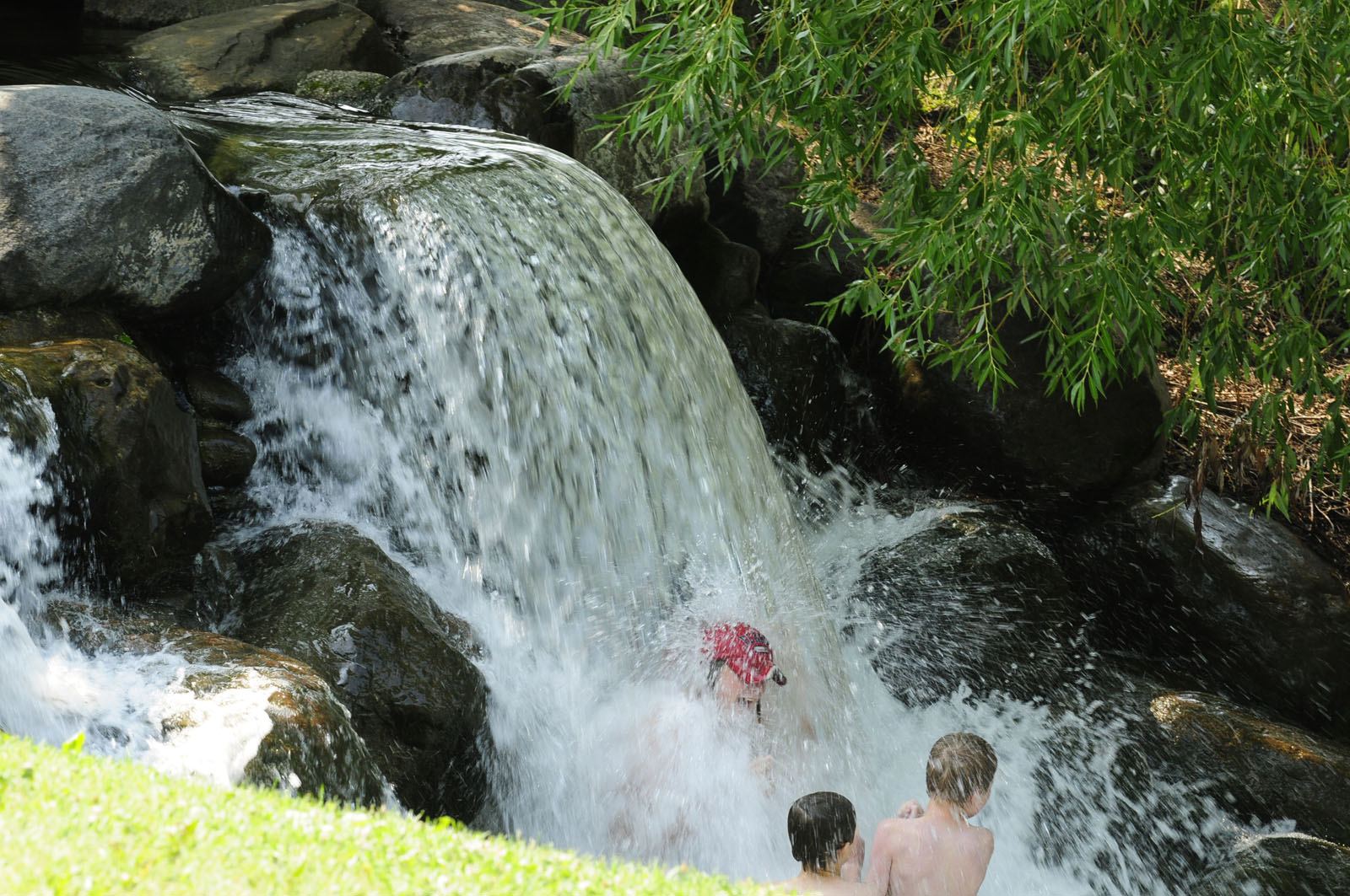 A youngster sticks his head out of the waterfall at Discovery Canyon in Red Deer recently to cool off from the summer heat.