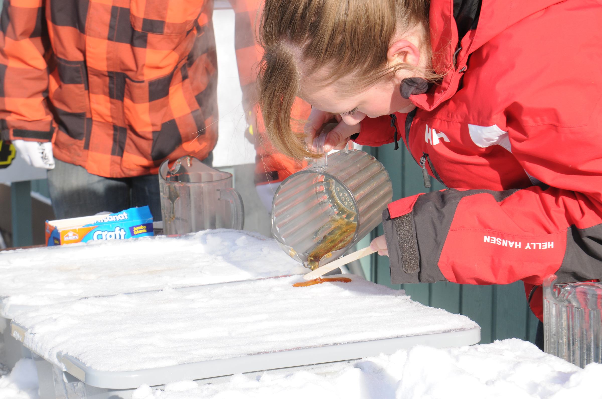SOMETHING SWEET- Amanda Beggs drizzles some maple syrup over some snow to make maple candy during the Snow Festival at Canyon Ski Resort this past weekend.