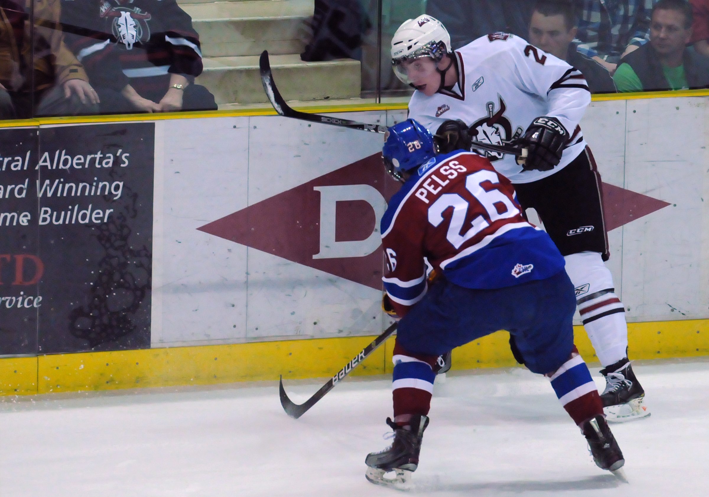 PASSING- Red Deer Rebel Justin Weller makes a quick pass as Kristians Pelss of Edmonton tries to intercept during WHL action Friday night. The Rebels won 5-0.