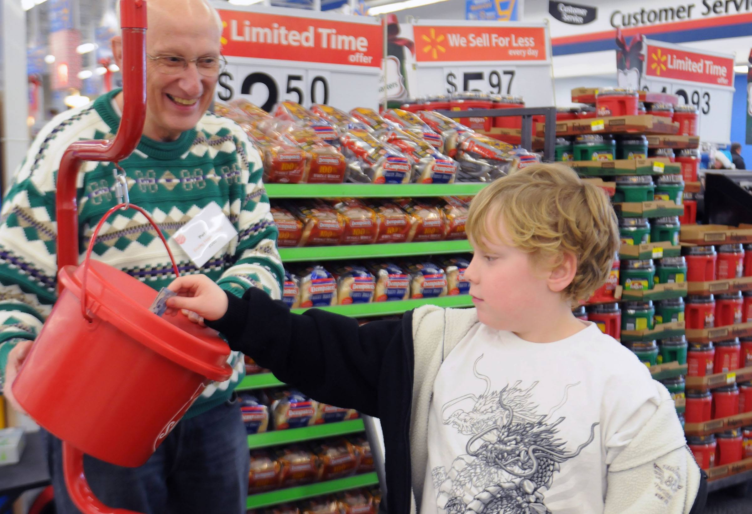SHARING- A local youngster contributes to the Salvation Army’s annual kettle campaign last year. This year’s campaign is underway at a number of sites around the City.