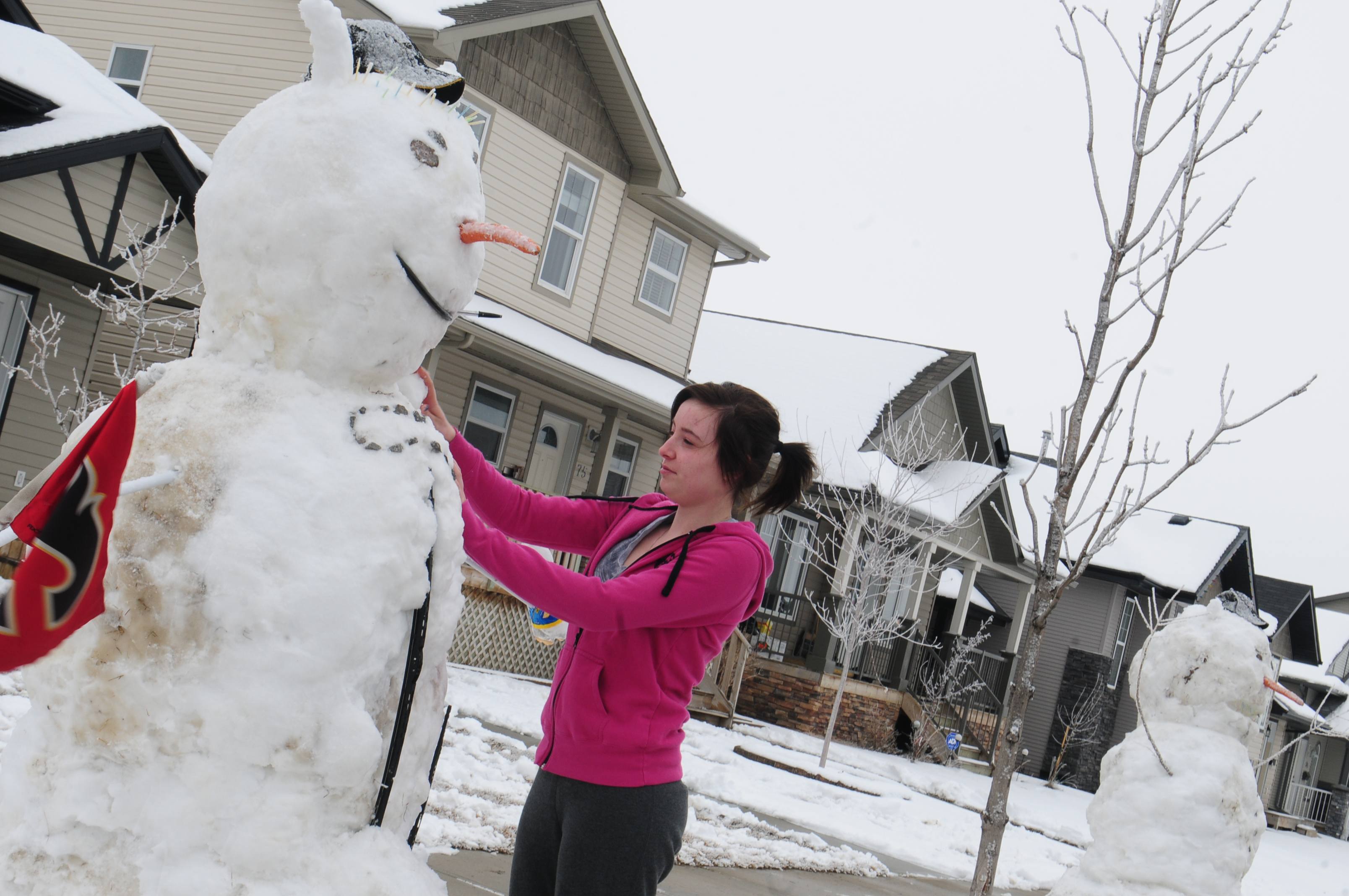 SNOW GIANTS- Brayanne Dawe fixes one of the giant snowmen that her boyfriend and his friend built in their front yard recently to get most of the snow off of the lawn.