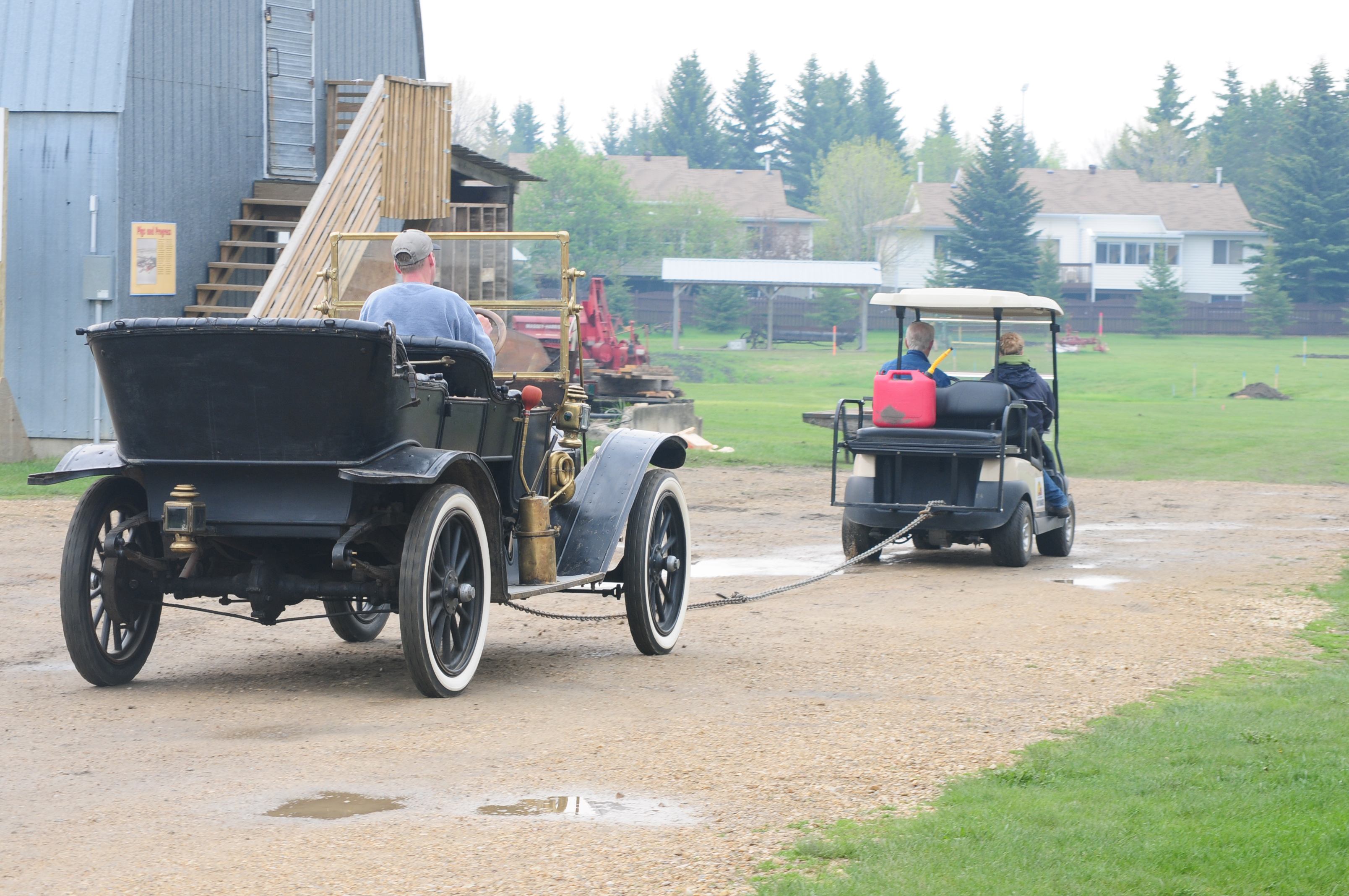 MOVING ALONG- A golf cart pulls an antique truck along at Sunnybrook Farm recently to try and start the old machine.