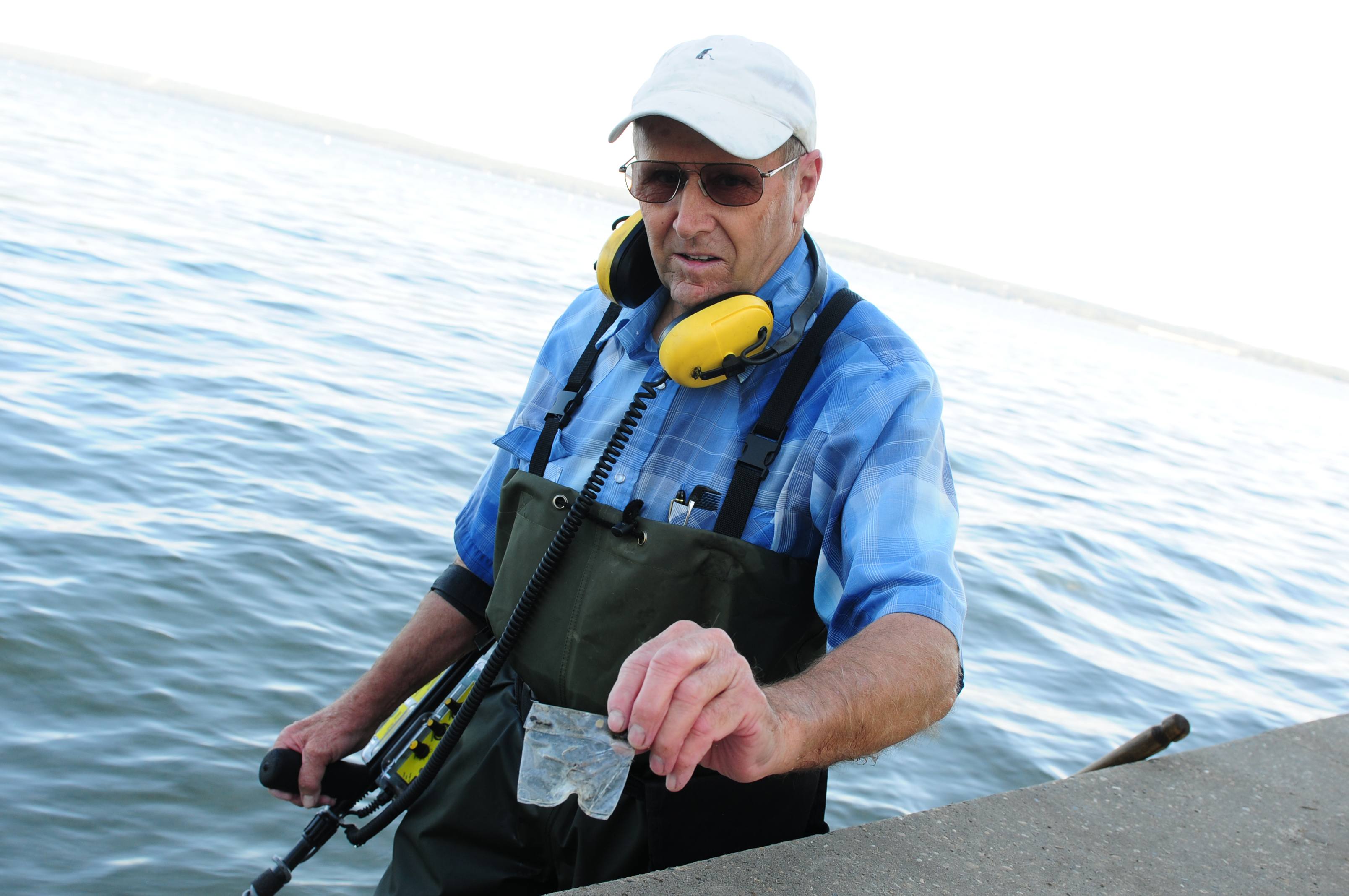 TRASH FIND- Martin McLaughlin holds up a bag of unused fishhooks he found while searching the lake bottom for trash and other metal items Friday morning.