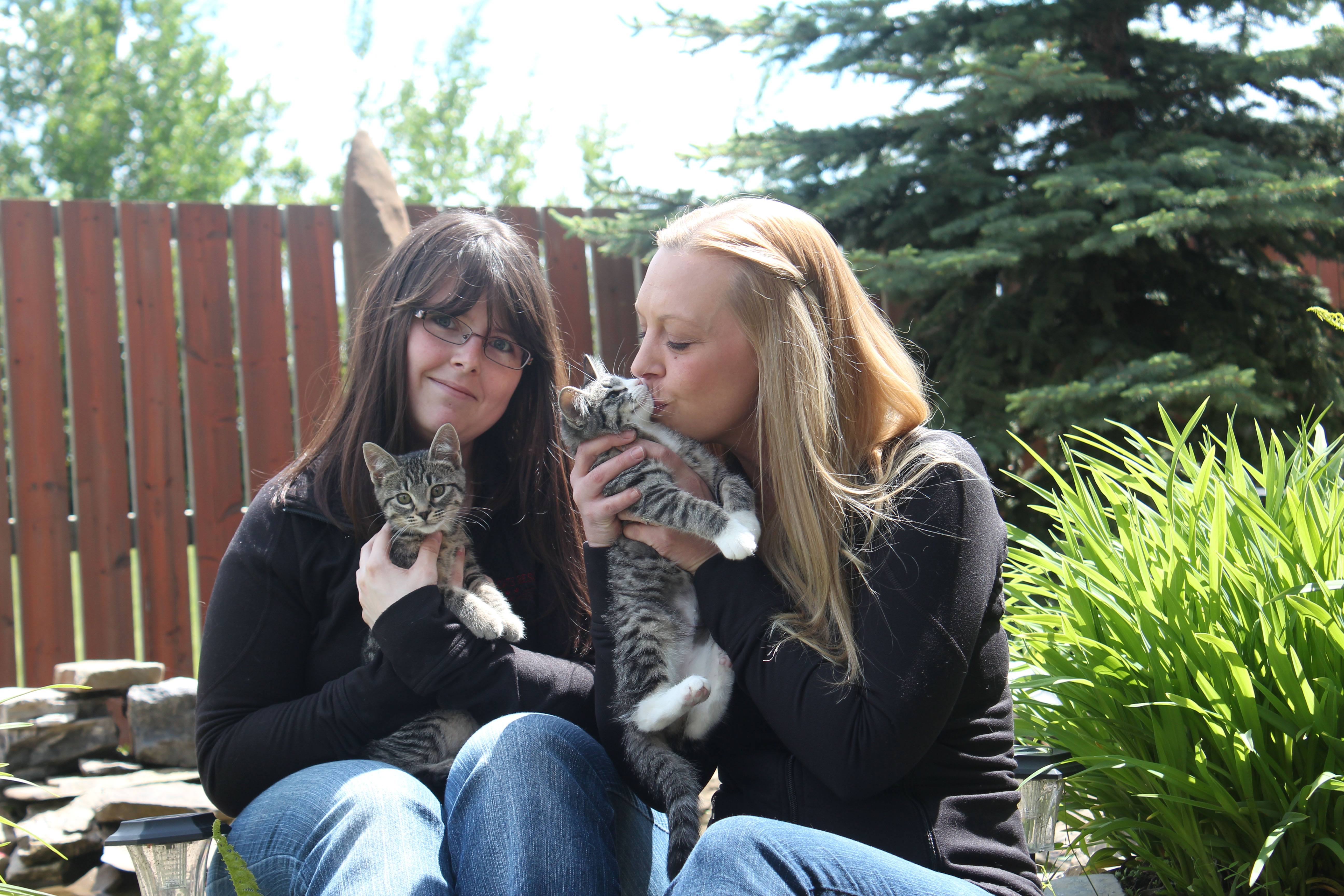 KITTEN CUDDLES - Tracy Hayden and Vanessa Caird cuddle with some of Alley Cats Rescue Society's kittens. The registered charity is holding a garage sale June 28-30.
