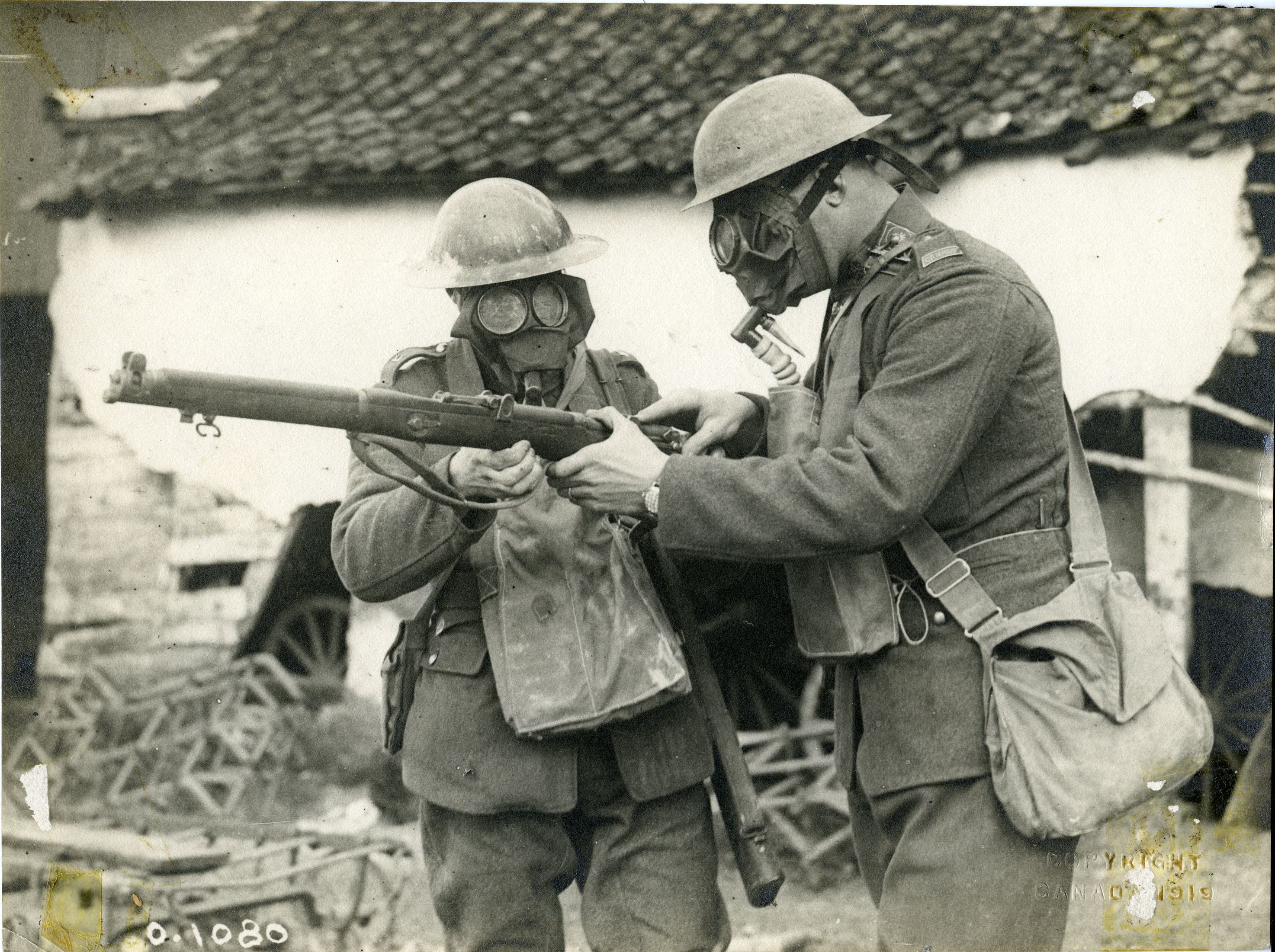FRIGHTENING TIMES - Two Canadian soldiers inspecting a rifle while wearing gas masks in Northern France during the First World War.