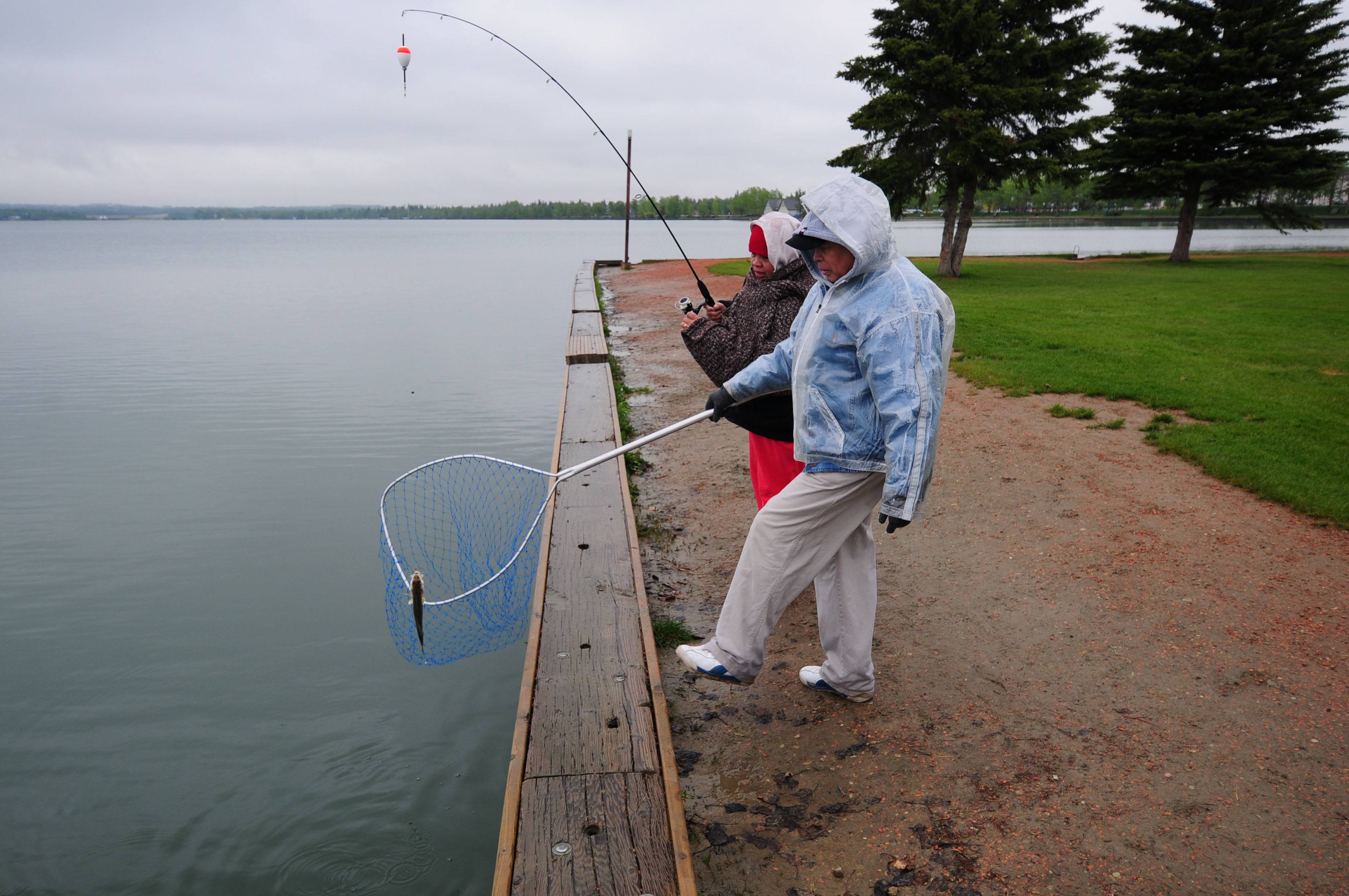 GREAT SPORT- Rey and Jessie Mahinay reel in a small pickerel fish that they caught at Sylvan Lake recently. The couple quickly released the small fish and continued to cast their line.