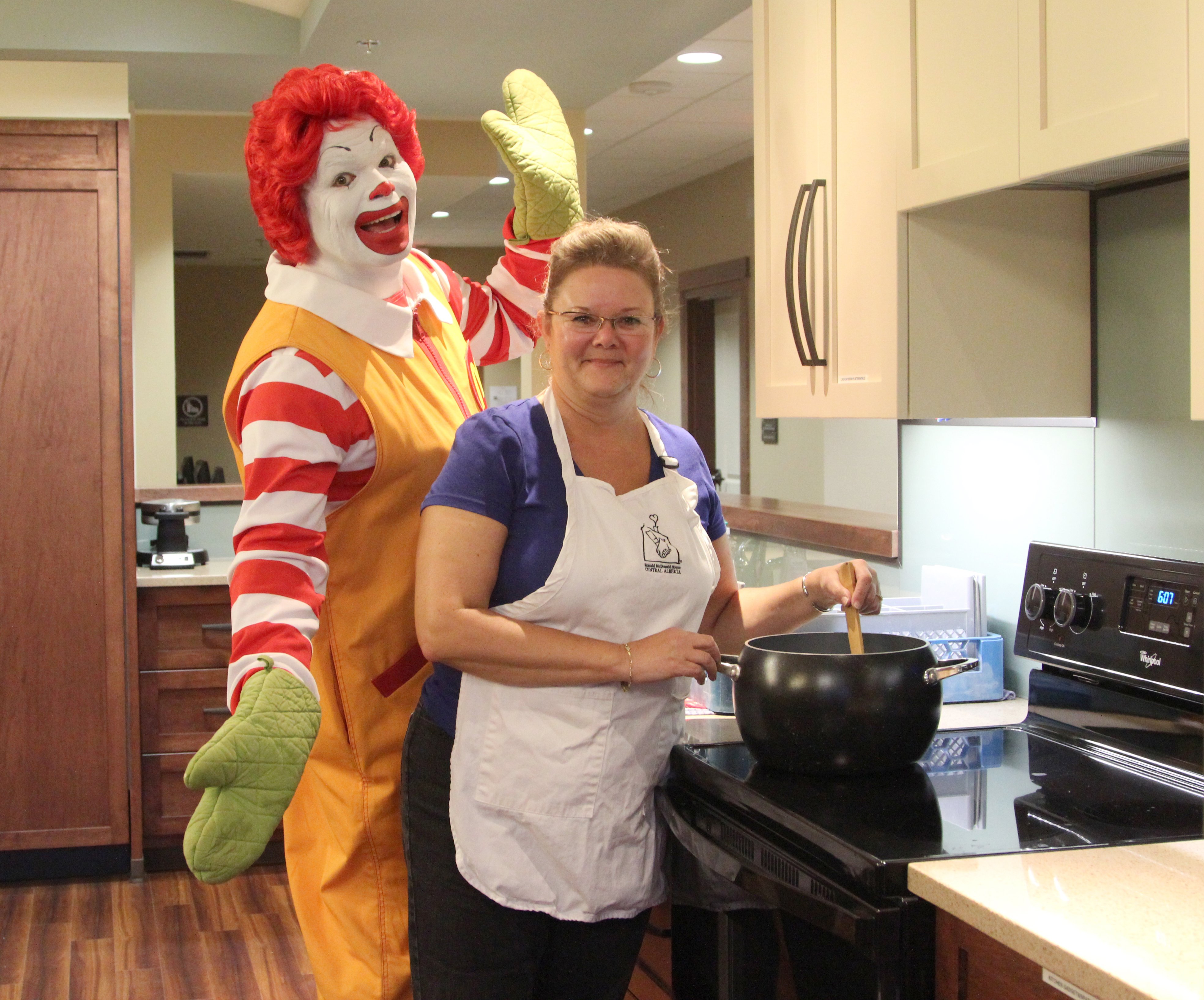 CELEBRATION – Ronald McDonald helps volunteer Shawna Allwright prepare a meal for guests at the House. The Ronald McDonald House is celebrating its first year anniversary today.