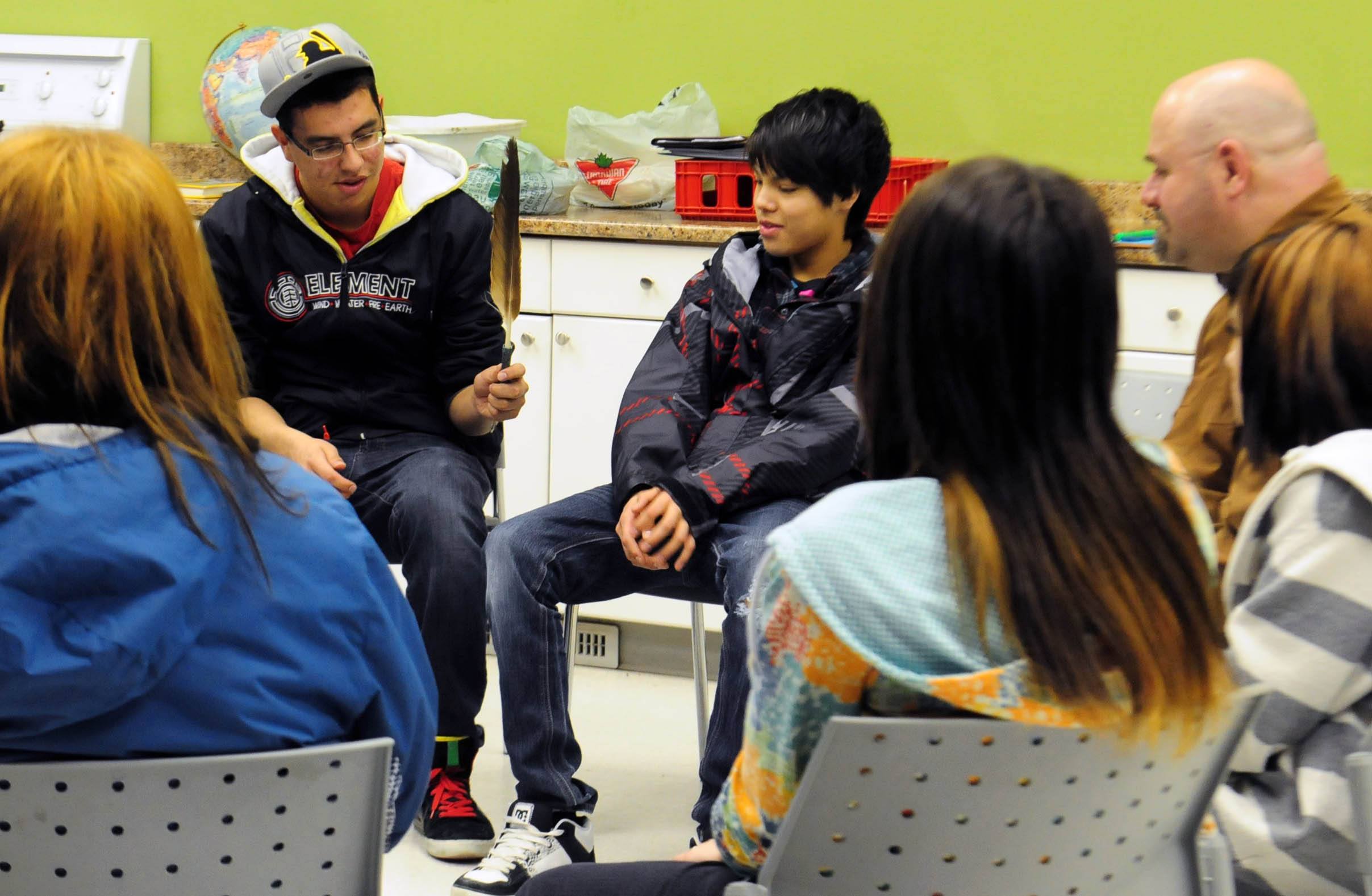 SACRED- Warren Simon passes an eagle feather to Koda Rabbit during a sharing circle at the Hub downtown recently. The group shared stories and learned about sacred aboriginal traditions.