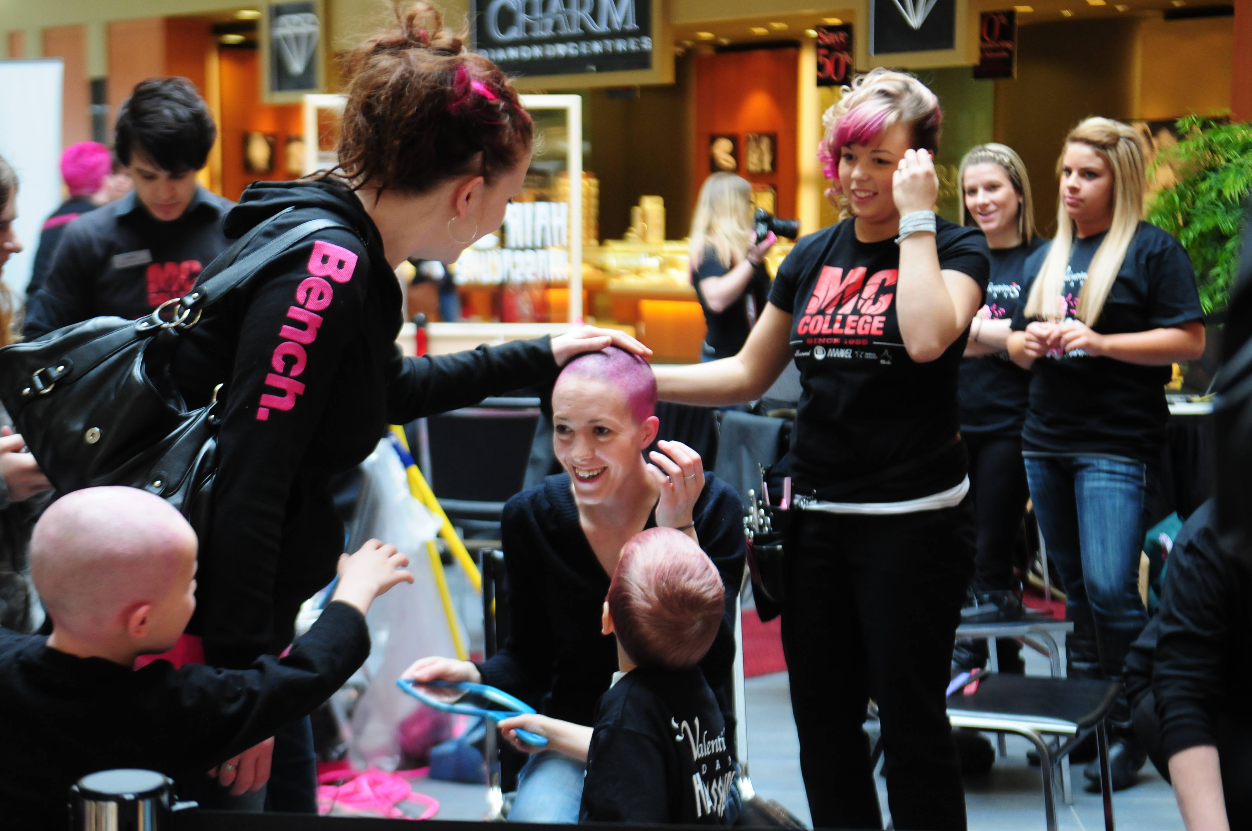 SMOOTH- Kristine Johnston lets her friend feel her head during the second annual Hair Massacure this past weekend at the Bower Mall. The event raised about $36