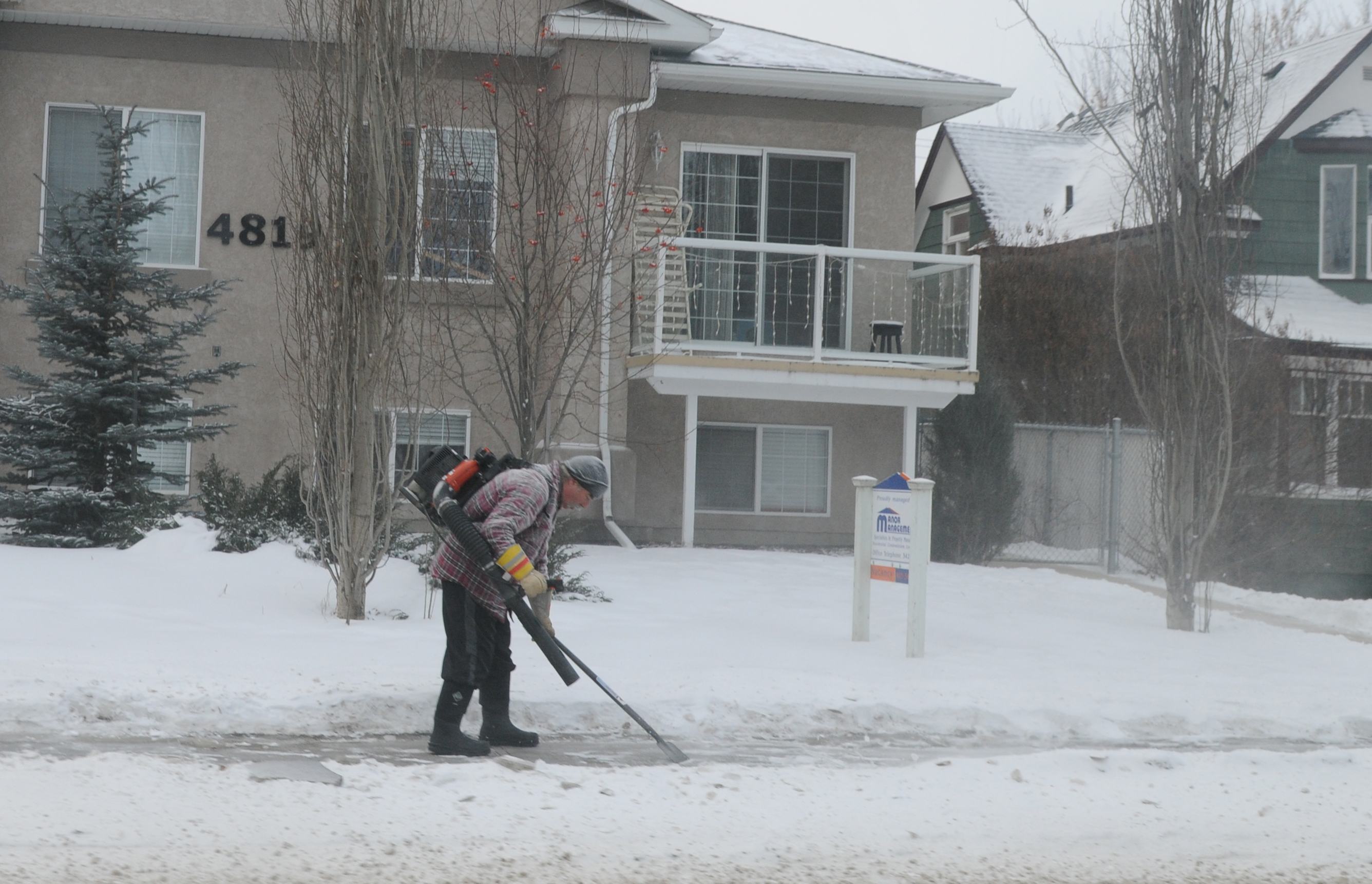 SAFETY- A man works on scraping the many layers of ice on a sidewalk for pedestrians recently.