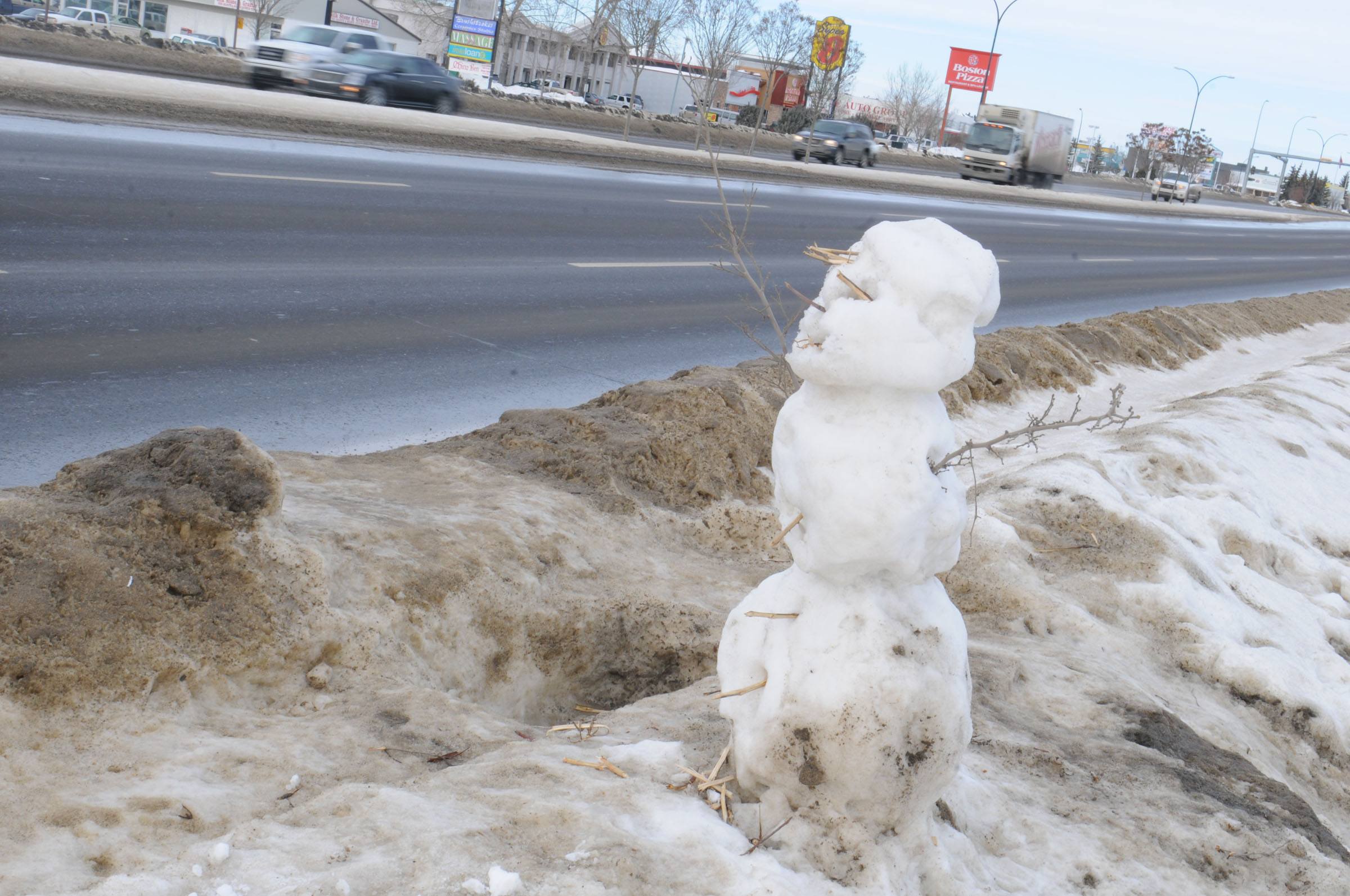 HITCHING A RIDE- A lone snowman sits as if waiting for a ride along 50 Ave North Red Deer by Prestige Furniture as cars fly by.