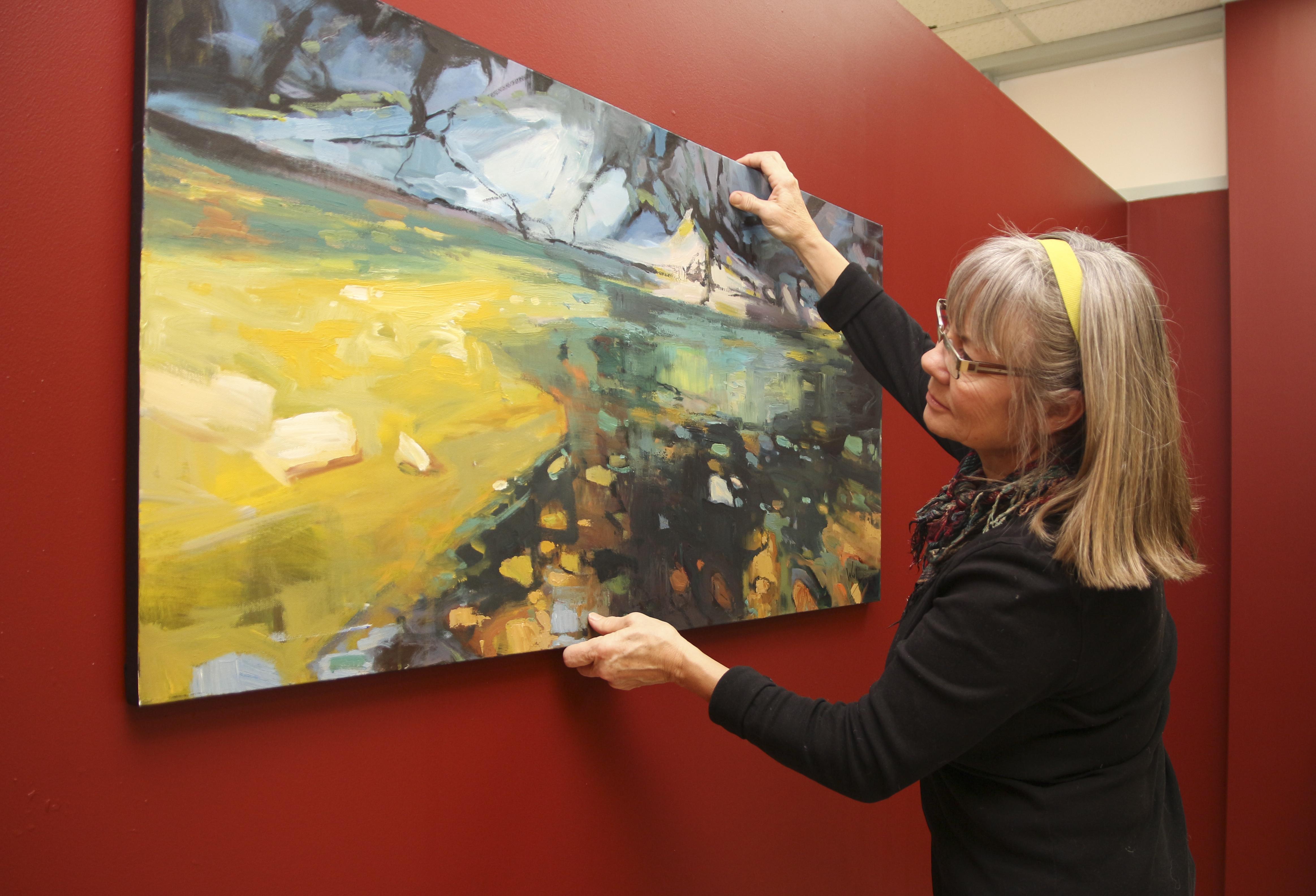 GETTING READY – Local professional artist Susan Woolgar adjusts one of her paintings as she displays her work in the Viewpoint Gallery