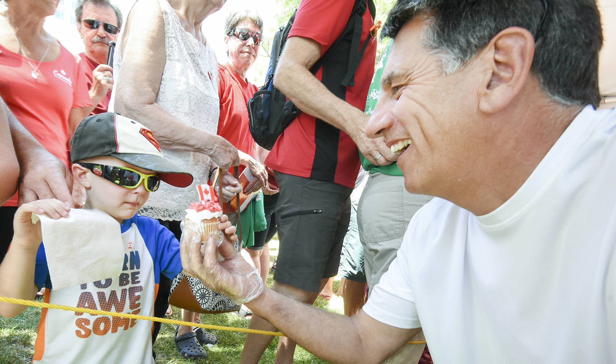 MLA Dan Ashton gives four-year-old Michael Gilbert a piece of the Canada Day cup cake at the ceremonies at Gyro Park. (Mark Brett/Penticton Western News)