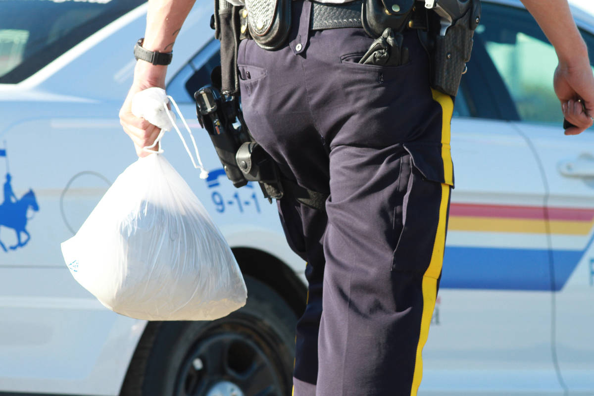 A Mountie carries evidence from the scene where an injured person was located in Ponoka.