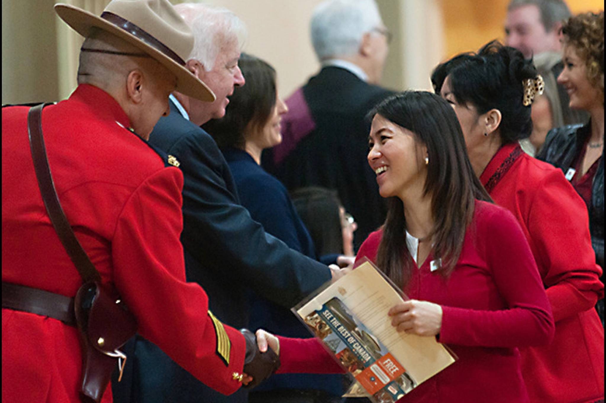 Phuong Nguyen, right, originally from Vietnam, is greeted by Oceanside RCMP Staff Sgt. Marc Pelletier after receiving her Canadian citizenship certificate. (Black Press Files)