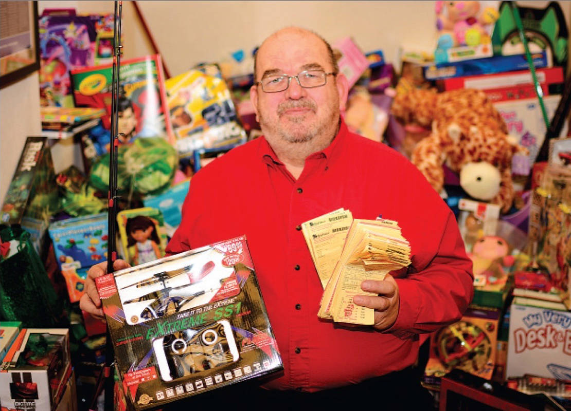 GIVING BACK - Fred Dieno, the City’s parking coordinator, stands in front of the dozens of toys that came in through the Toys For Tickets program in a previous year. Express file photo