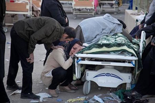 In this photo provided by Tasnim News Agency, relatives weep over the body of an earthquake victim, in Sarpol-e-Zahab, western Iran, Monday, Nov. 13, 2017. (Farzad Menati/Tasnim News Agency via AP)
