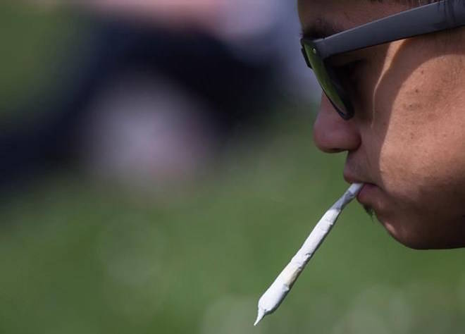 A man holds a joint between his lips during the annual 4-20 cannabis culture celebration at Sunset Beach in Vancouver on April 20, 2017. THE CANADIAN PRESS/Darryl Dyck