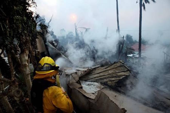 A firefighter hoses down smoldering debris in Ventura, Calif., Tuesday, Dec. 5, 2017. (Daniel Dreifuss via AP)