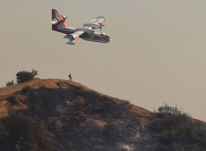 In this photo provided by the Santa Barbara County Fire Department, a Bombardier 415 Super Scooper aircraft comes in for a water drop below East Camino Cielo in the hills above Montecito, Calif., Sunday morning, Dec. 17, 2017. (Mike Eliason/Santa Barbara County Fire Department via AP)