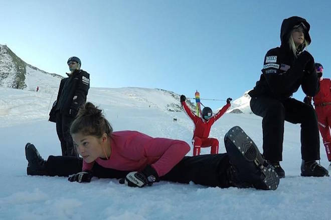 This photo taken from a 4K video and dated Tuesday, Oct. 17, 2017 shows Ashley Caldwell, front, and other members of the US and Swiss aerial skiing national teams warming up before training in Saas-Fee, Switzerland. Because snow is no longer guaranteed early in the season at their headquarters in Park City, Utah, she and other members of the US aerials national team went to train high on the Saas-Fee glacier ahead of the 2018 Pyeongchang Olympics. (AP Photo/John Leicester)