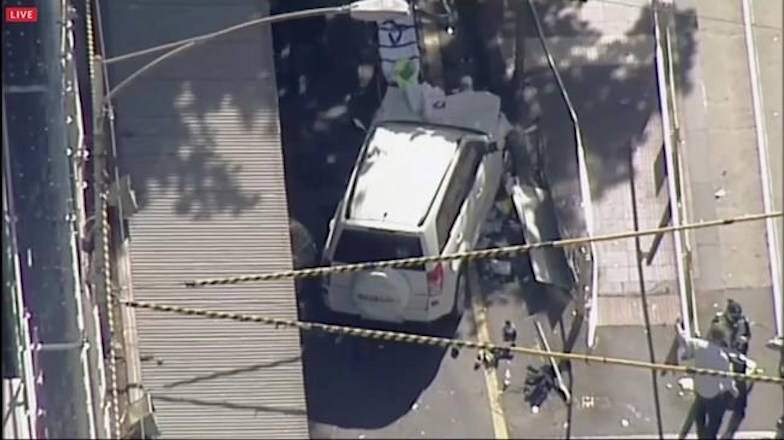 In this photo made video from the Australian Broadcasting Corp., a white SUV vehicle is stopped after allegedly striking pedestrians, Thursday, Dec. 21, 20217, in Melbourne, Australia. Local media say over a dozen people have been injured after a car drove into pedestrians on a sidewalk in central Melbourne. (Australian Broadcast Corp. via AP)