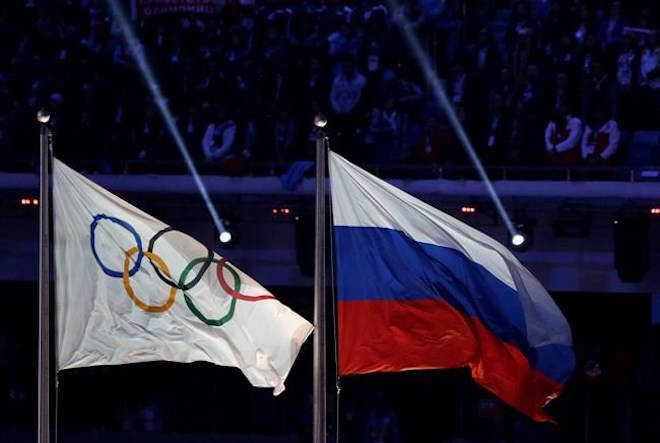 FILE - In this Feb. 23, 2014 file photo, the Russian national flag, right, flies next to the Olympic flag during the closing ceremony of the 2014 Winter Olympics in Sochi, Russia. The word “Russia” will appear on the Olympic uniforms worn by the athletes granted an exemption from the country’s doping ban. More than 200 athletes are set to compete in Pyeongchang as an “Olympic Athlete from Russia” if they can prove they aren’t tainted by doping. (AP Photo/Matthias Schrader, File)