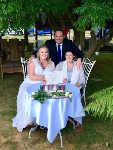 In this photo provided by Rodney Croome, Lainey Carmichael, left, Roz Kitschke, right, and celebrant Jason Betts pose as they show Lainey and Roz’s marriage certificate at their home in Franklin, south of Hobart, Australia Tuesday, Jan. 9, 2018. (Rodney Croome via AP)