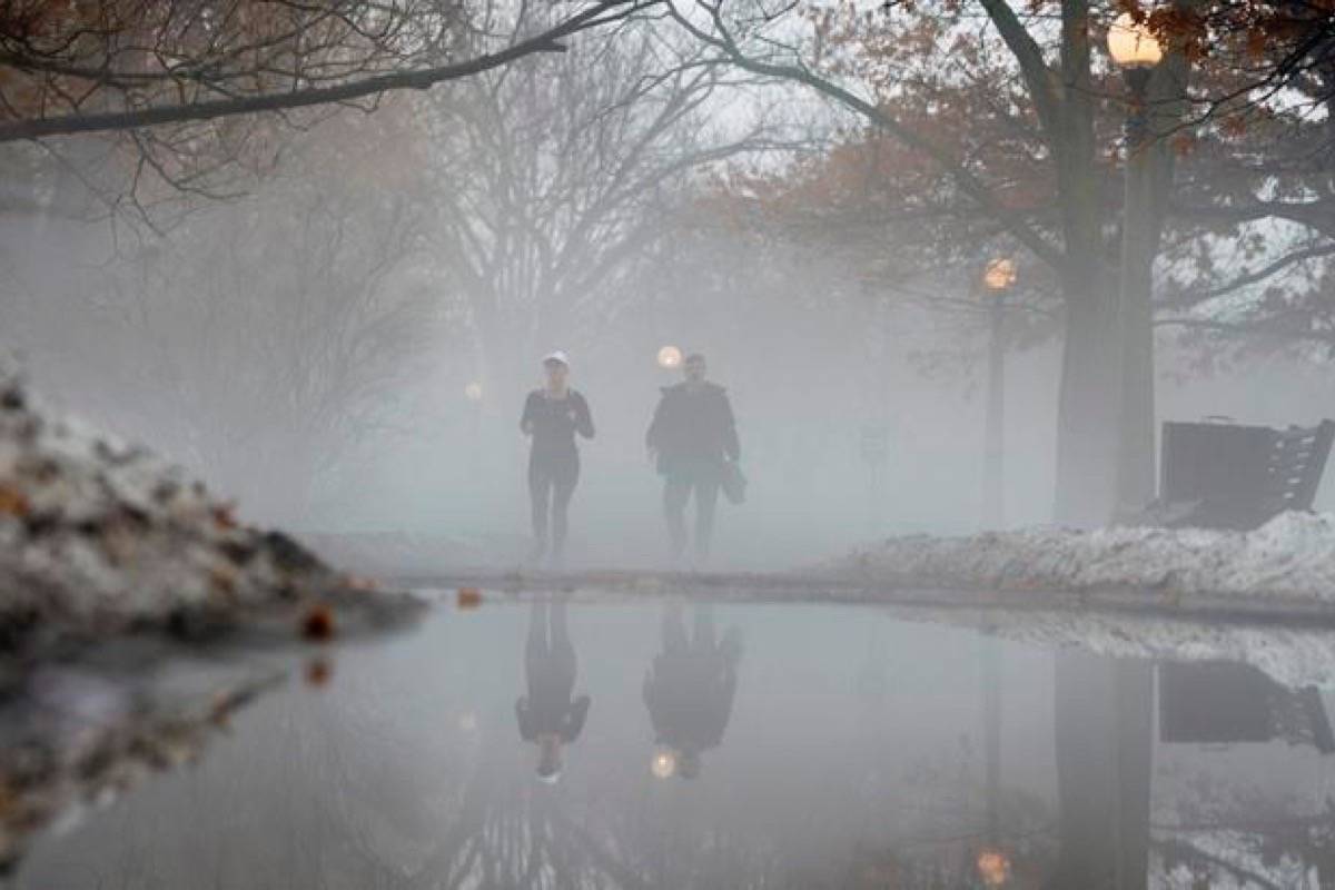 A jogger passes a man walking along a foggy pathway Friday in Ottawa. (Adrian Wyld/The Canadian Press)