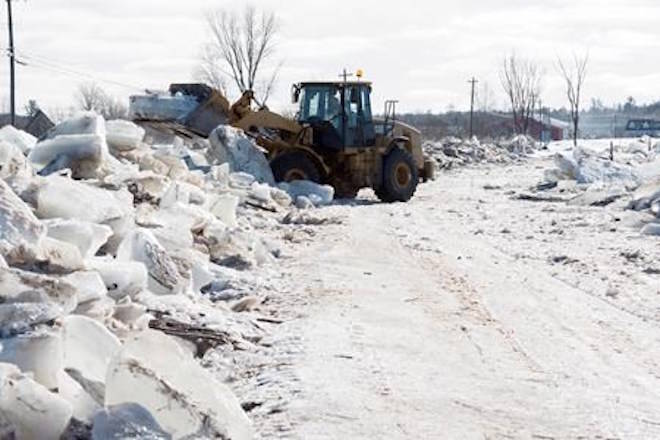 Tim McCann uses a front end loader to remove ice off of Route 101 in Hoyt, N.B., on Sunday, January 14, 2018. Heavy rain flooded the road on Saturday floating large ice onto the road and dropping temperatures then froze the water overnight into Sunday morning. THE CANADIAN PRESS/Stephen MacGillivray