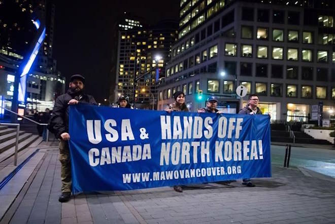 Protesters carry a banner while marching outside the site of a summit on North Korea being hosted by Canada and the U.S., in Vancouver, B.C., on Monday January 15, 2018. Foreign ministers from 20 countries are meeting Tuesday to discuss security and stability on the Korean Peninsula. THE CANADIAN PRESS/Darryl Dyck