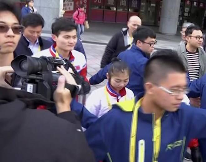 In this image made from video, North Korean figure skaters Ryom Tae-ok, center, and Kim Ju-sik, center left, are guarded as they leave Taipei Arena after a practice session in Taipei, Taiwan, Monday, Jan. 22, 2018. The North Korean figure skating pair, who will compete in the Winter Olympics in South Korea next month, are in Taiwan this week to take part in a competition. (TVBS via AP)