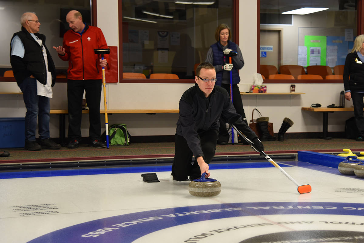 FREEZE THE HOUSE - Jeff Ireland, Team Collins Barrow, throws the rock at the Ronald McDonald House 7th Annual Charity Bonspiel with Olympic curler Kevin Martin looking on in the background. Michelle Falk/Red Deer Express