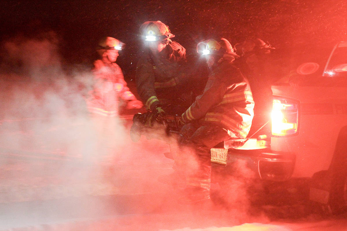 Once the patient was loaded onto a spinal board, firefighters hold him steady on the back of the pickup in order to get him to EMS. At the time of the incident, snow and wind created a cold evening. Photo by Jeffrey Heyden-Kaye