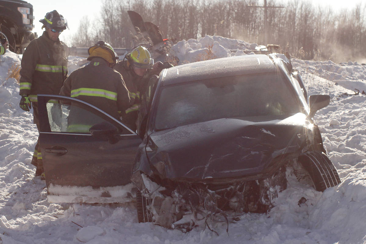 Members of the Ponoka County East District Fire Department inspect a vehicle involved in a collision with a train Sunday afternoon. The occupants are believed to have suffered minor injuries from the incident and the tracks were expected to be closed for some time.                                Photo by Jeffrey Heyden-Kaye