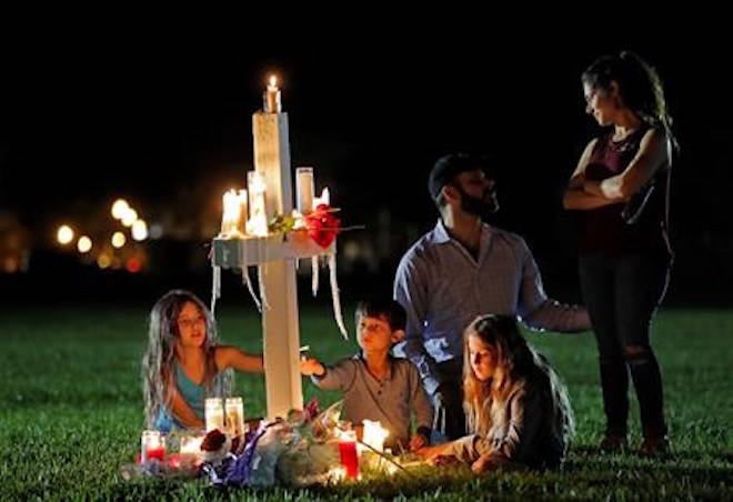 Rich and Rachel Castleberry visit one of seventeen crosses after a candlelight vigil for the victims of the Wednesday shooting at Marjory Stoneman Douglas High School, in Parkland, Fla., Thursday, Feb. 15, 2018. Nikolas Cruz, a former student, was charged with 17 counts of premeditated murder on Thursday. With them are their children Mila, 9, left, Jack, 5, center, and Lucy, 7. (AP Photo/Gerald Herbert)