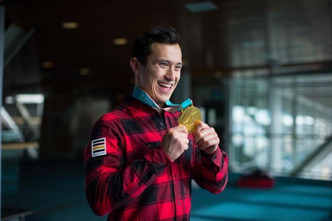 Figure skater Patrick Chan of Toronto holds his 2018 Olympic gold medal after arriving from South Korea at Vancouver International Airport on Monday. (Darryl Dyck/The Canadian Press)